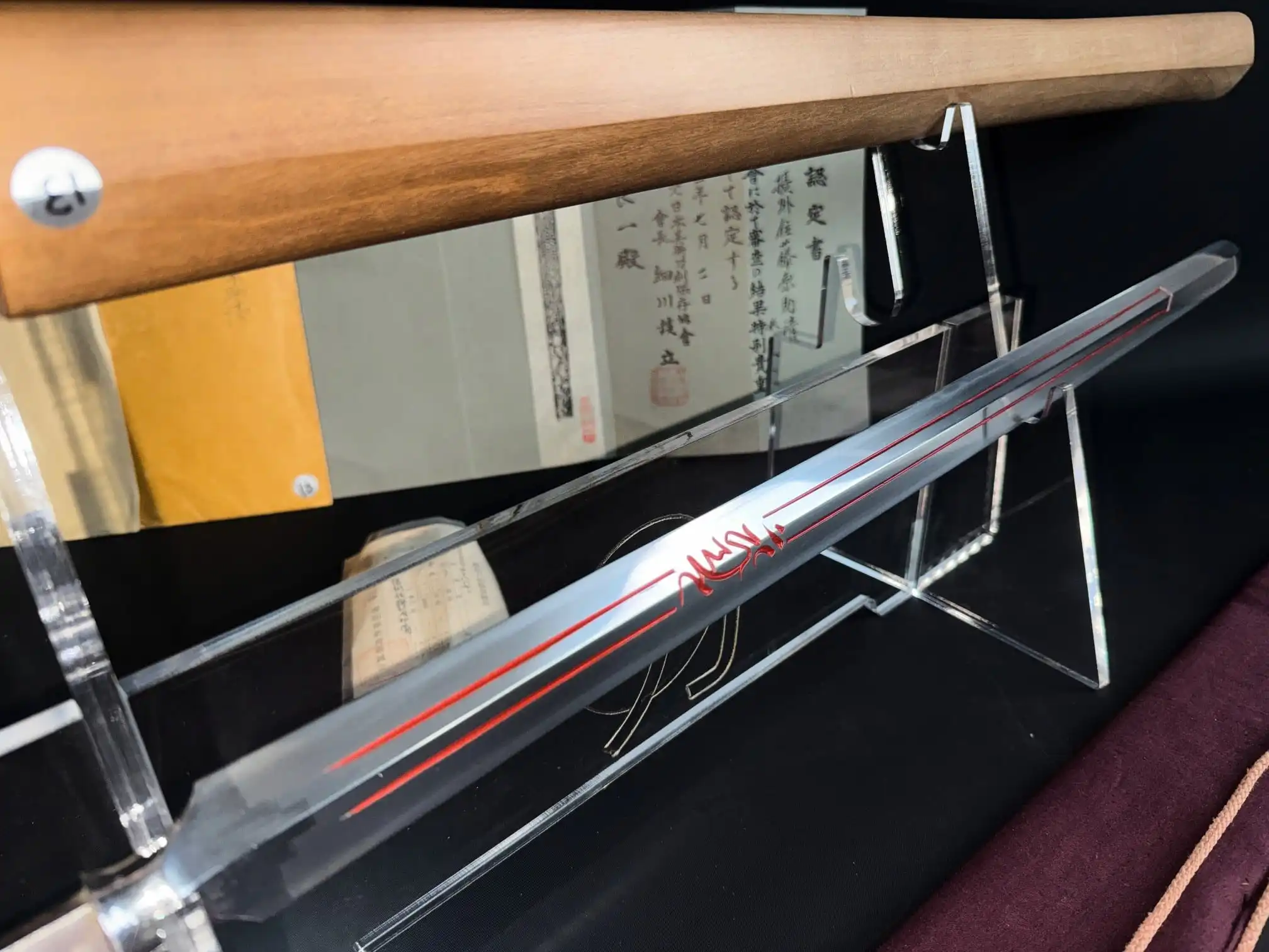 Ōmi Yari Sukekiyo Yari / Naginata on stand, showing the blade's red inlay and wooden scabbard