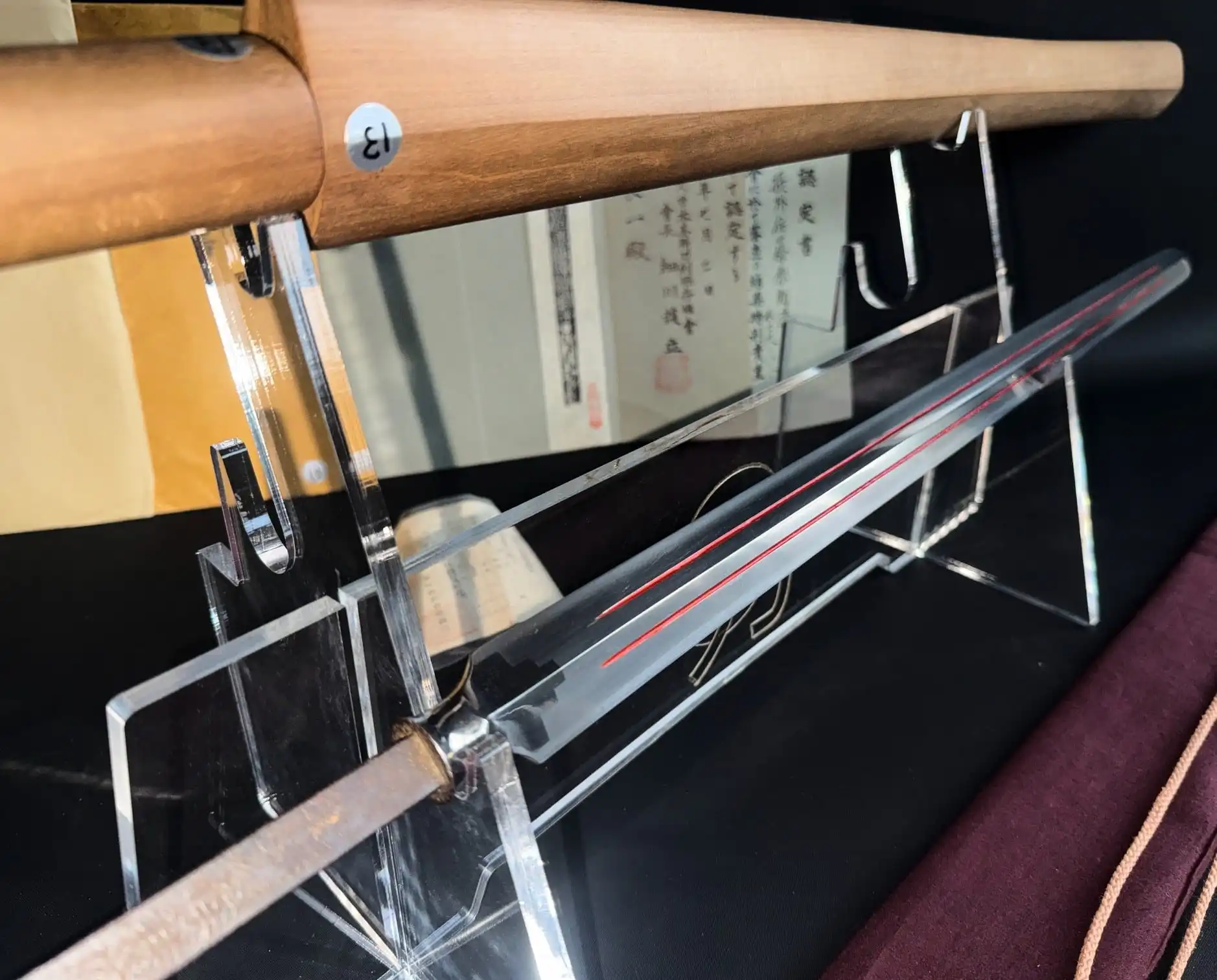Ōmi Yari Sukekiyo yari / naginata with red lacquered grooves on clear display stand, sword bag below