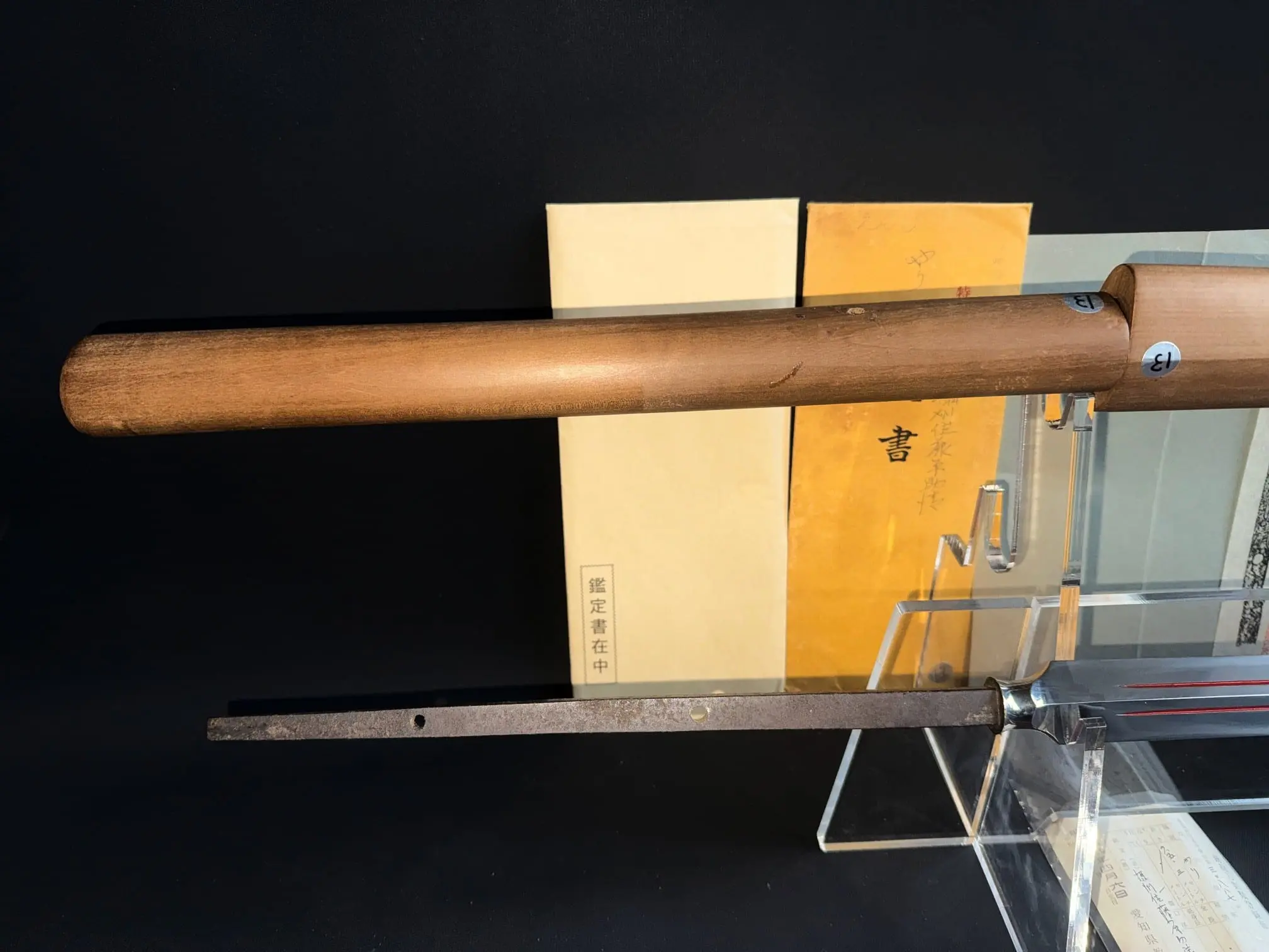 Close-up of Ōmi Yari Sukekiyo Naginata tang with wooden handle and certificate in background