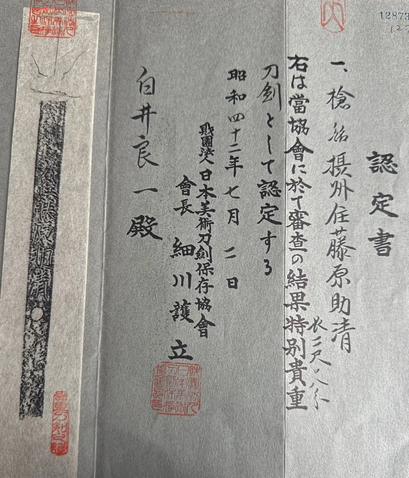 Top-down view of Japanese calligraphy and red stamps on paper, part of the Ōmi Yari Sukekiyo Yari Naginata certificate