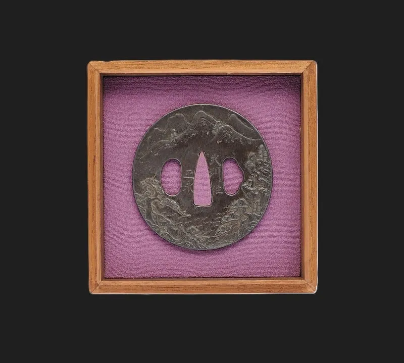 Tsuba Busyu Masanaga, dark Edo-Period tsuba with ornate dragon and mountain relief, displayed in a wooden box