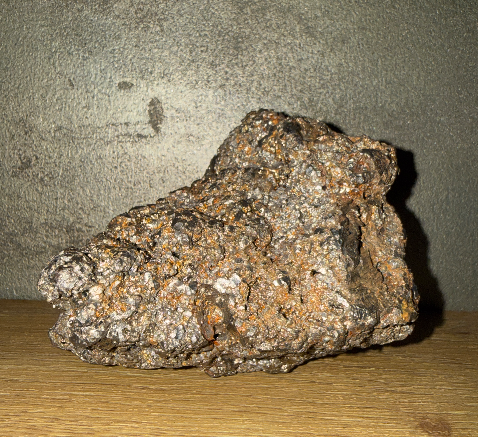 Rough, dark 1.361 kg Japanese Tamahagane Steel accessory with silvery and orange flakes, shot from the side