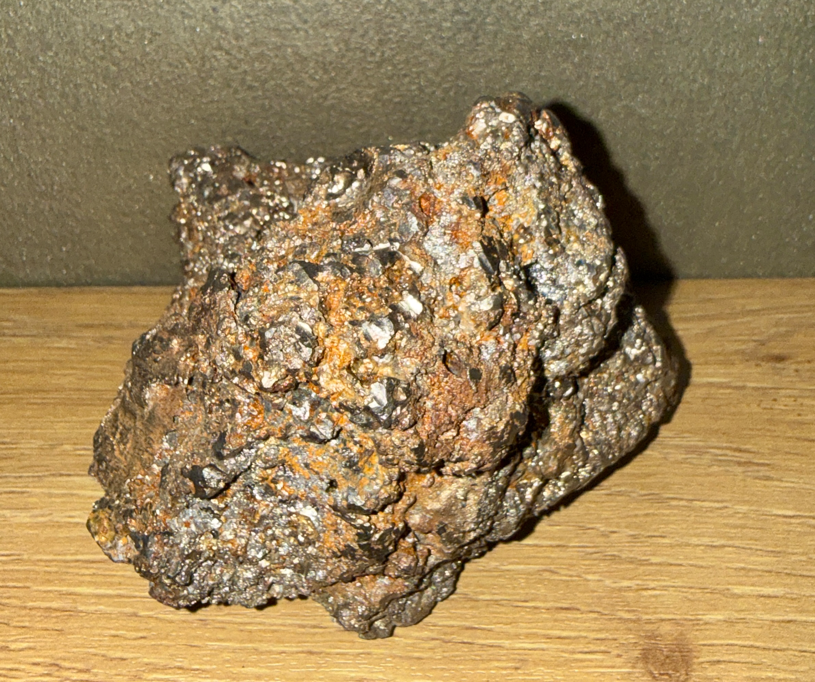 Rough, sparkling Japanese Tamahagane Steel accessory against a wood surface