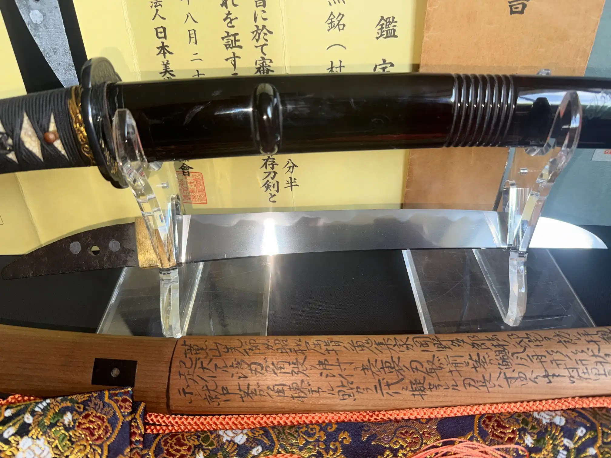 Close-up of a Nidai Muramasa Sayagaki katana, blade partially sheathed, intricate writing on wooden saya