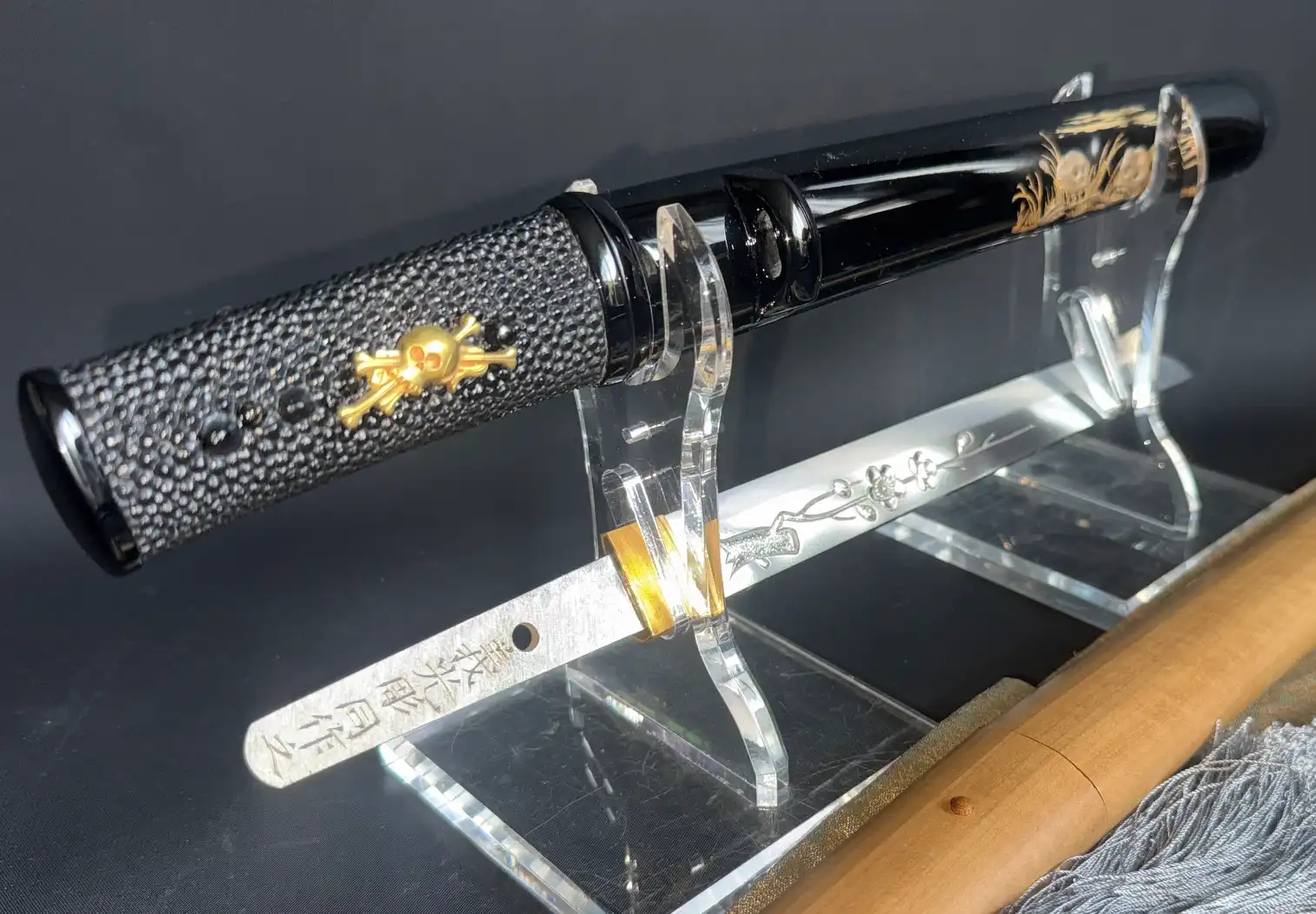 Ōno Yoshimitsu Mukansa Tantō with skull motif on handle, blade with flower engraving, on clear display stand