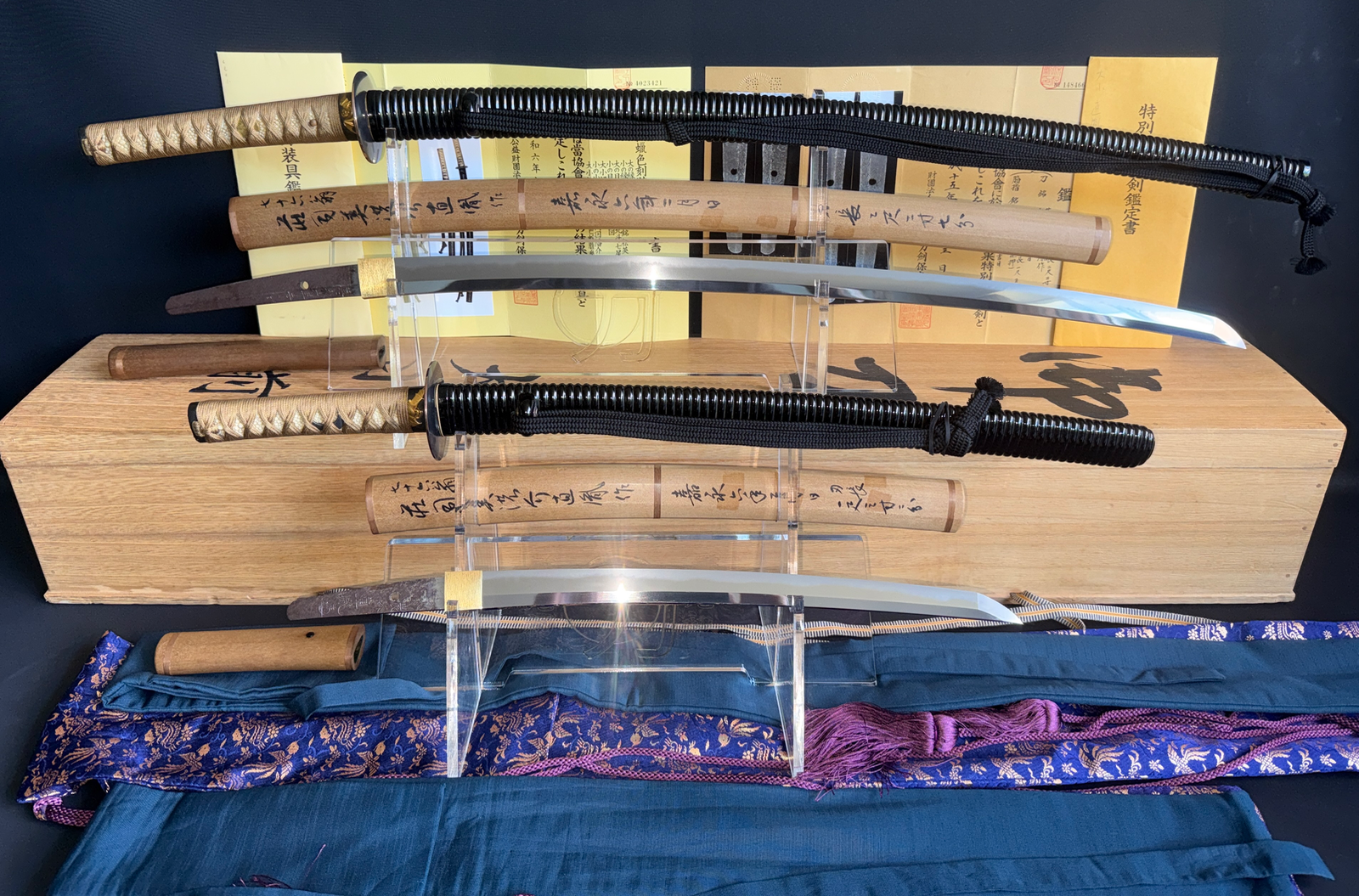 Naotane's Final Known Daishō katana blades with their handles and scabbards on stands, documents behind.