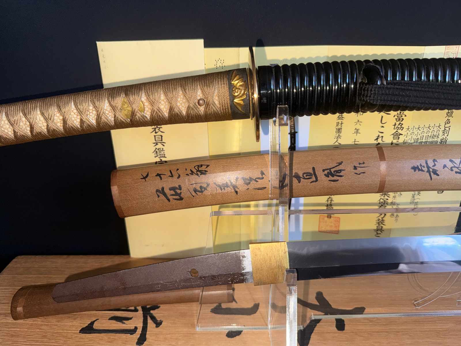 Close-up of Naotane’s Final Known Daishō katana, showing tsuka, saya, and exposed blade on a stand.