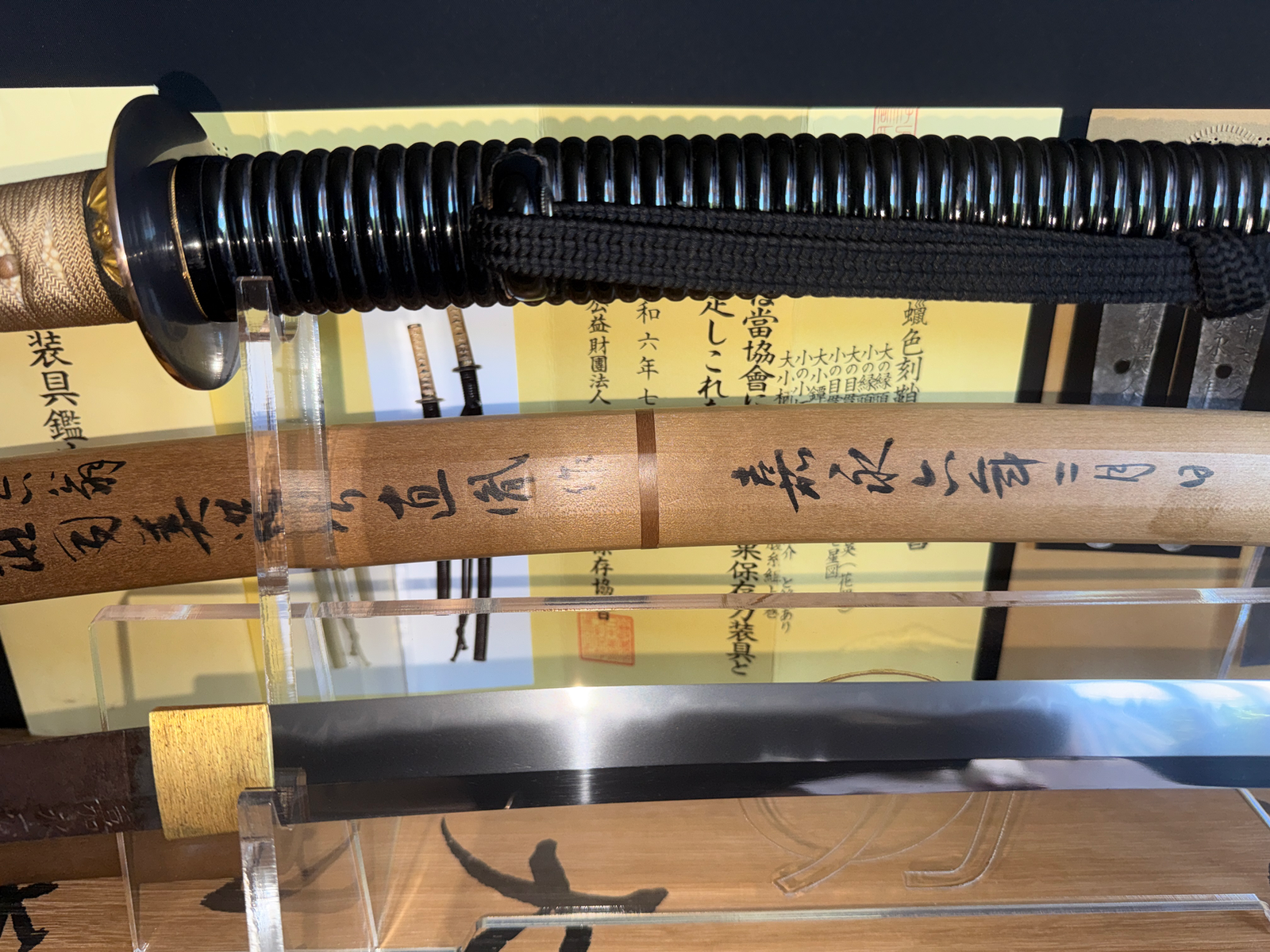 Close-up of a Taikei Naotane's Final Known Daishō katana, showing handle, hilt, wooden scabbard with kanji.
