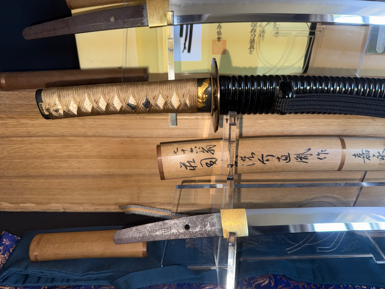 Naotane's Final Known Daishō katana with ornate handle and glossy black sheath on display