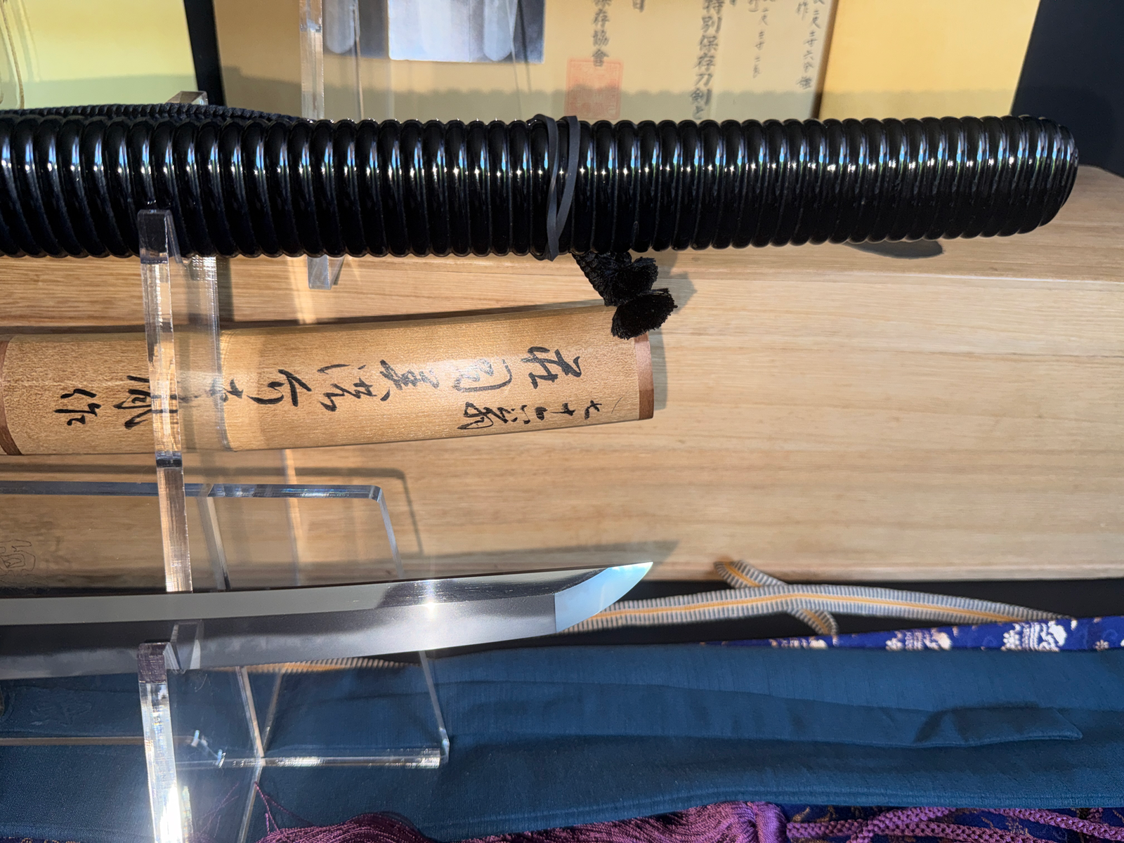 Naotane's Final Known Daishō katana, with black lacquered saya and visible tip, resting on a wooden surface