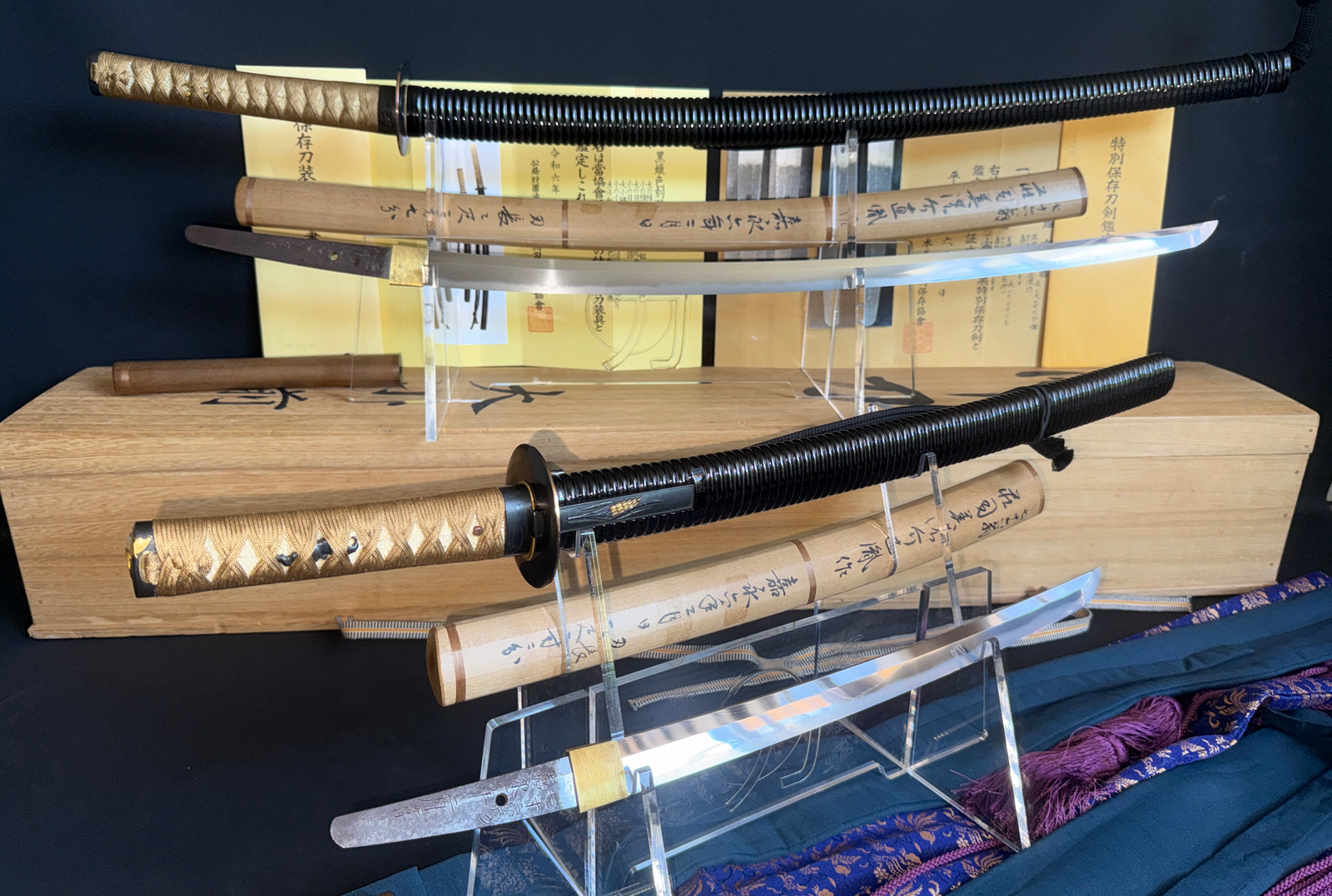 Naotane’s Final Known Daishō katana pair on stands, with wooden boxes and appraisal papers visible.