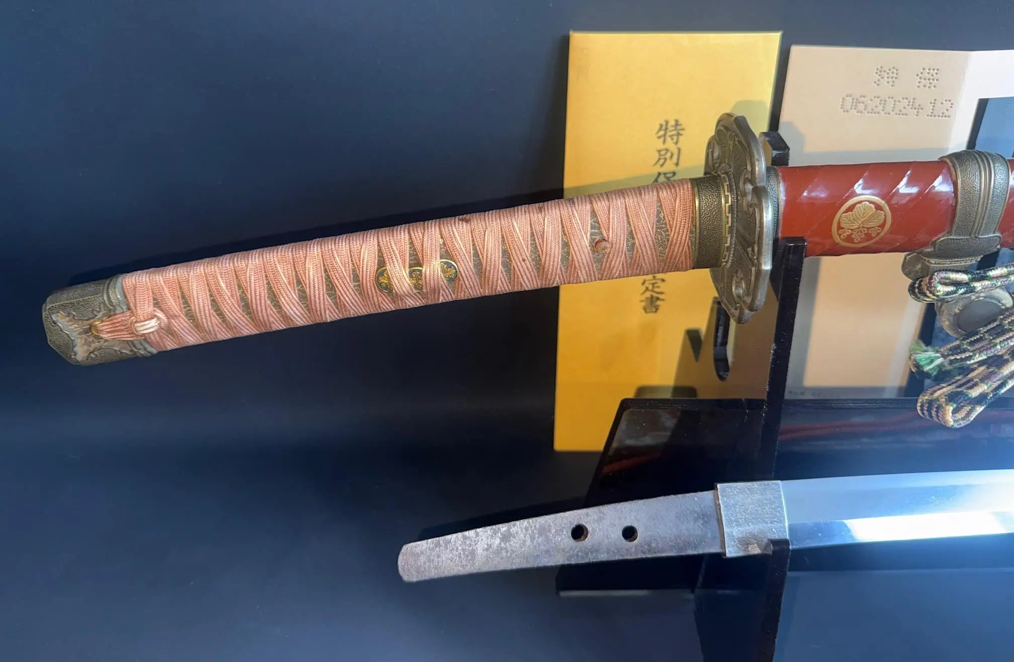 Nanbokuchō Tachi Hidemitsu katana, close-up of the handle with pink wrap and red saya with gilt emblem
