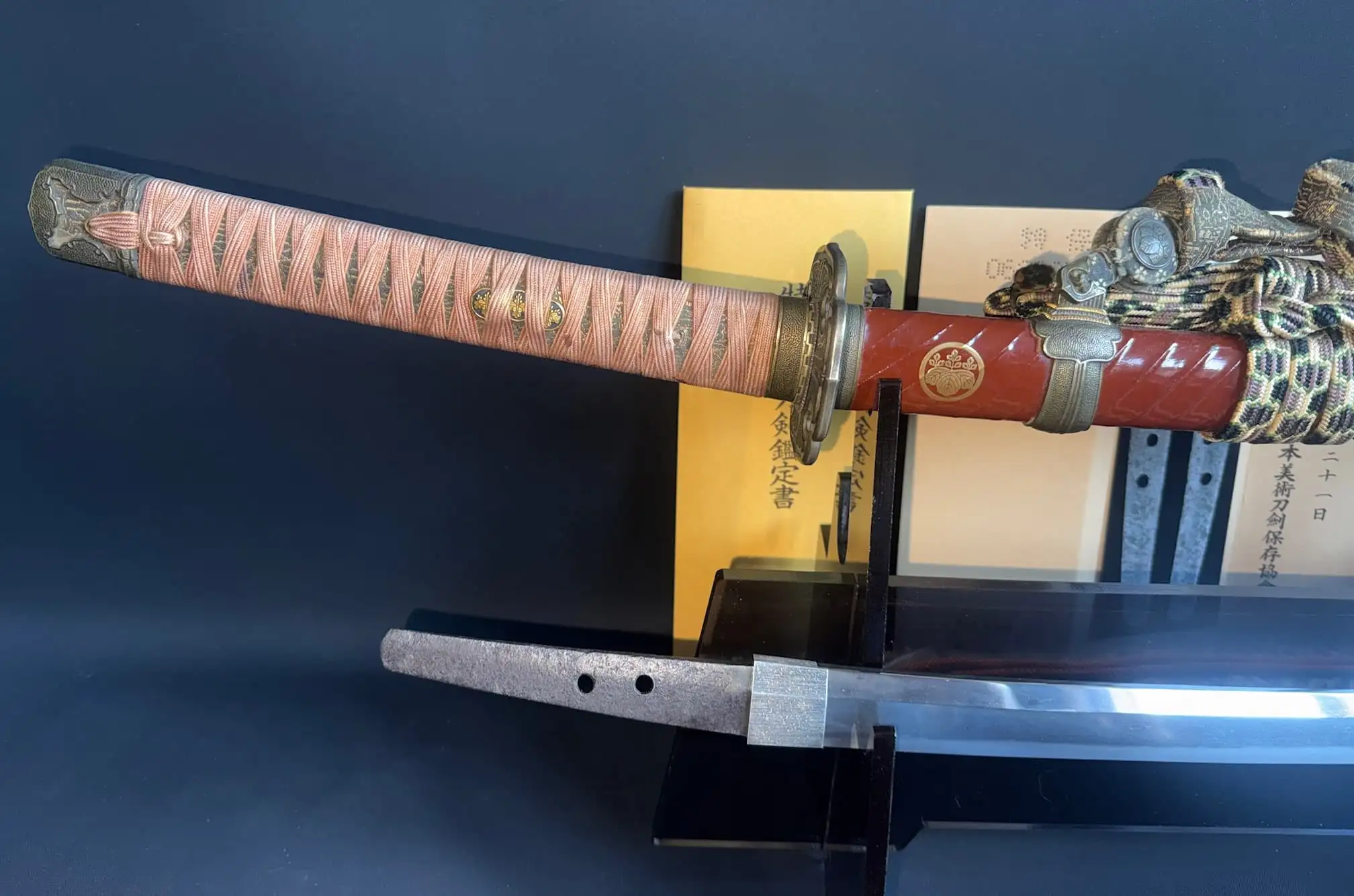 Close-up of a Nanbokuchō Tachi Hidemitsu katana with intricate handle wrap and red scabbard