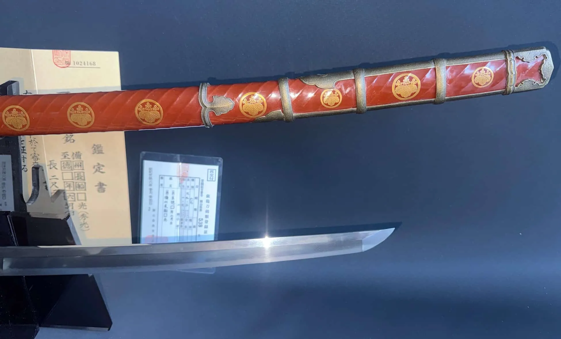 Side view of Nanbokuchō Tachi Hidemitsu Katana with red lacquered saya and certifications.