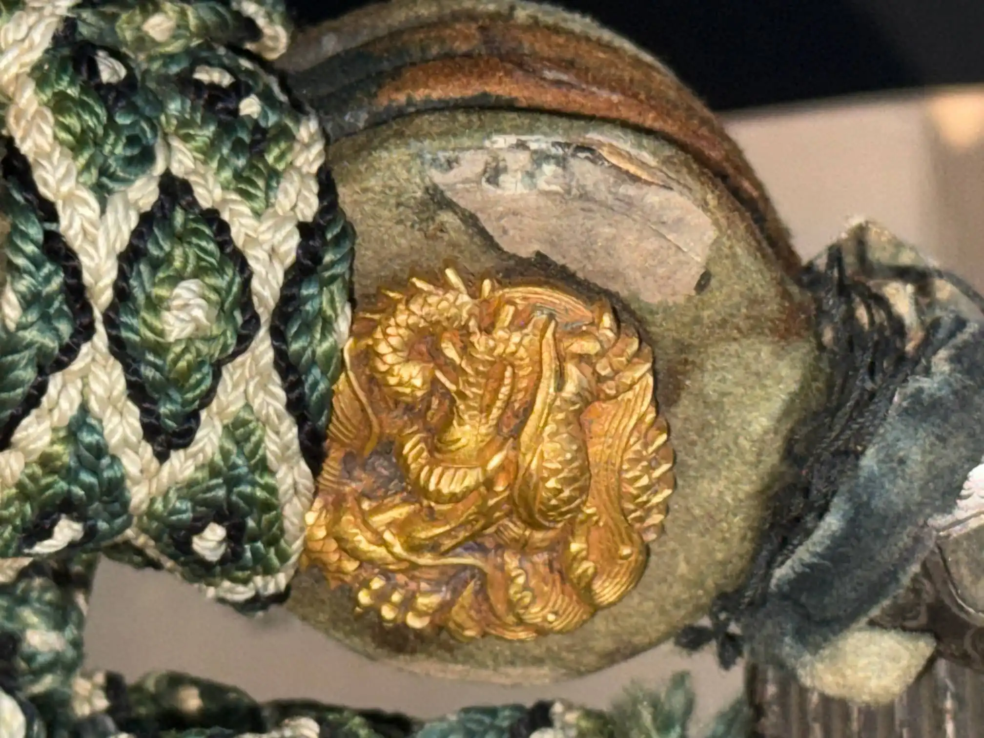 Close-up of golden dragon menuki on a Tachi Yokoyama Sukekane Katana with green and white tsuka-ito.