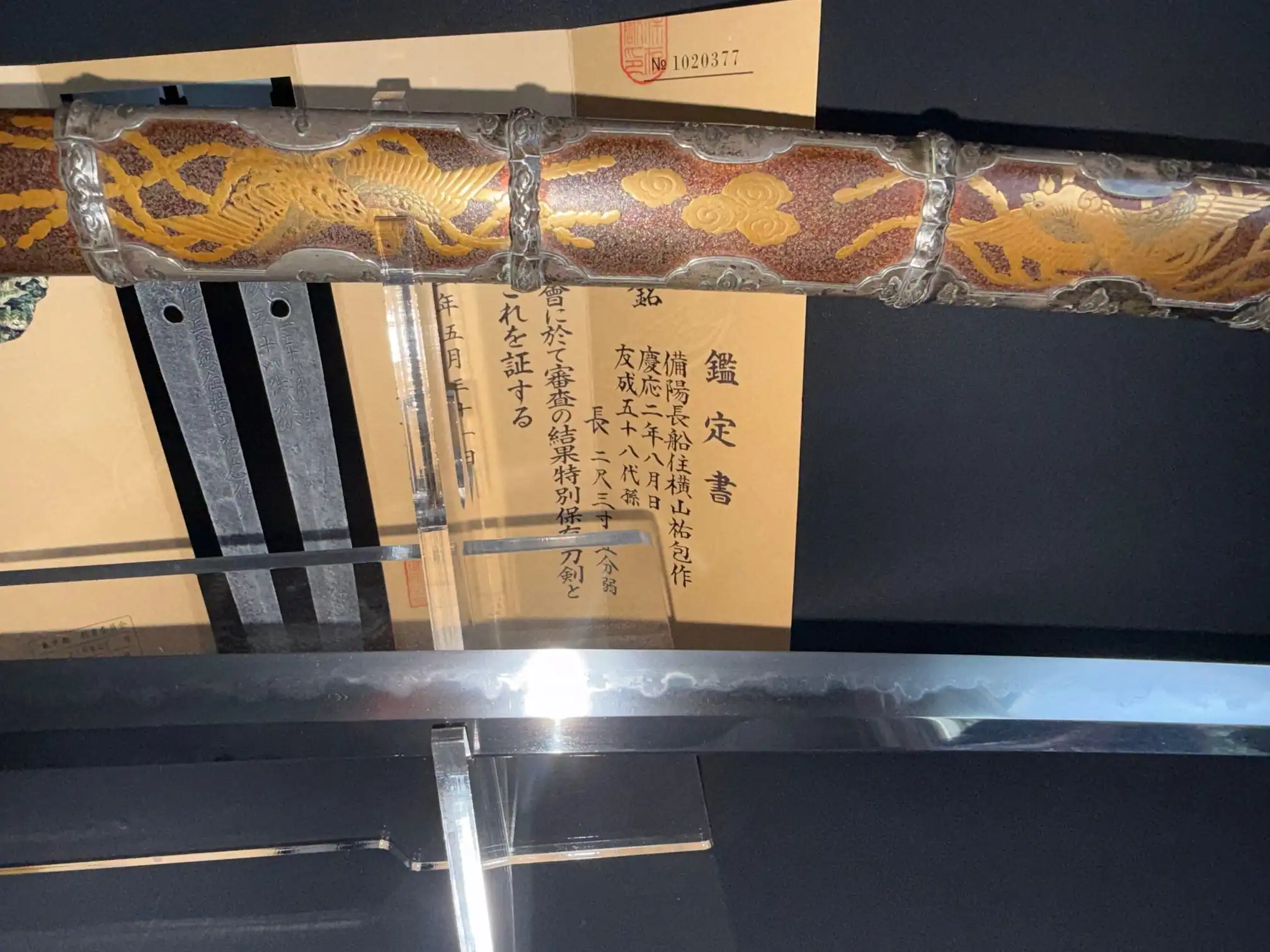 Tachi Yokoyama Sukekane Katana with ornate scabbard, paperwork visible, and detailed blade section on display.