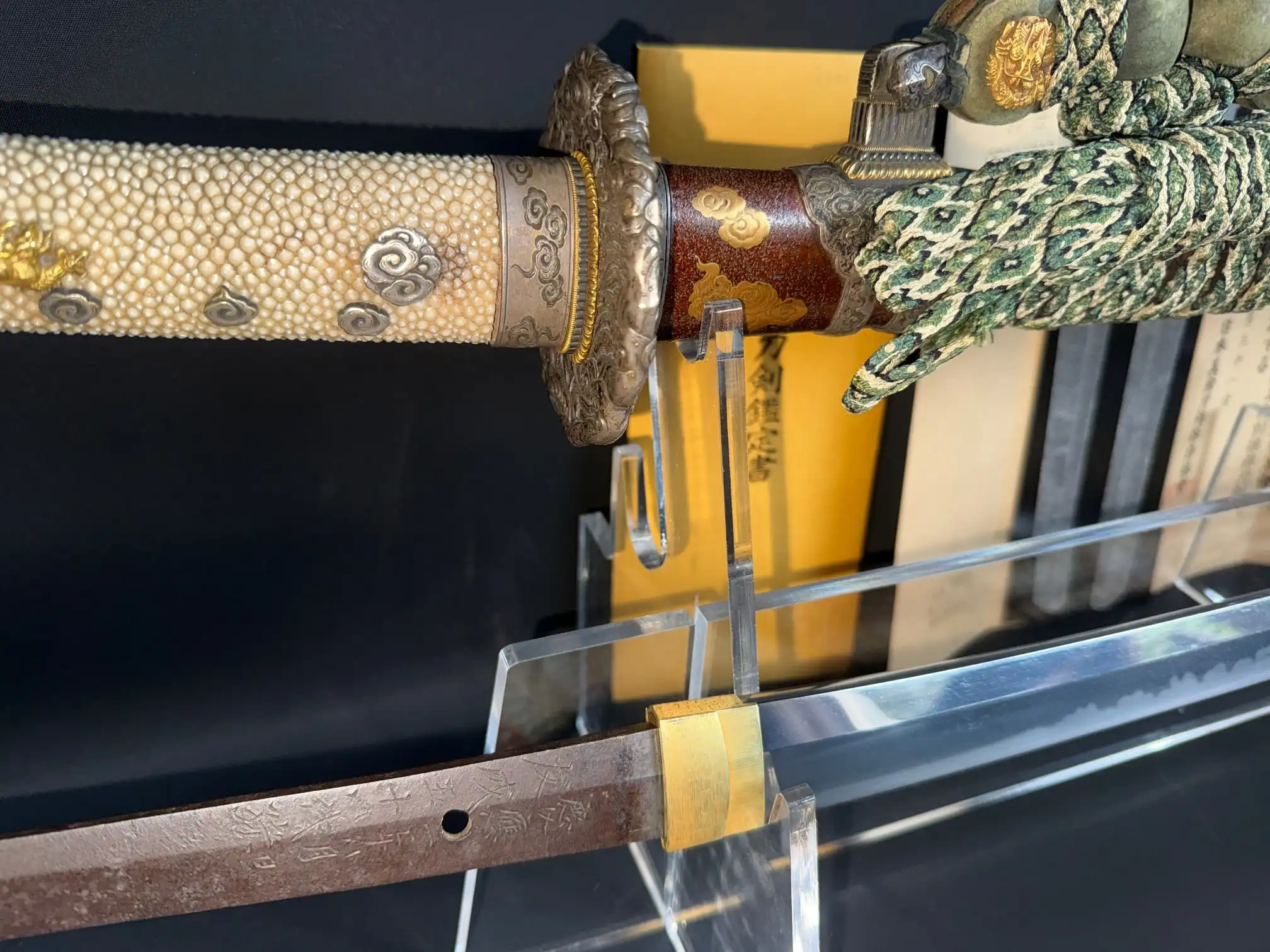 Close-up of Tachi Yokoyama Sukekane Katana with hilt, tsuba, and partially sheathed blade visible on display.