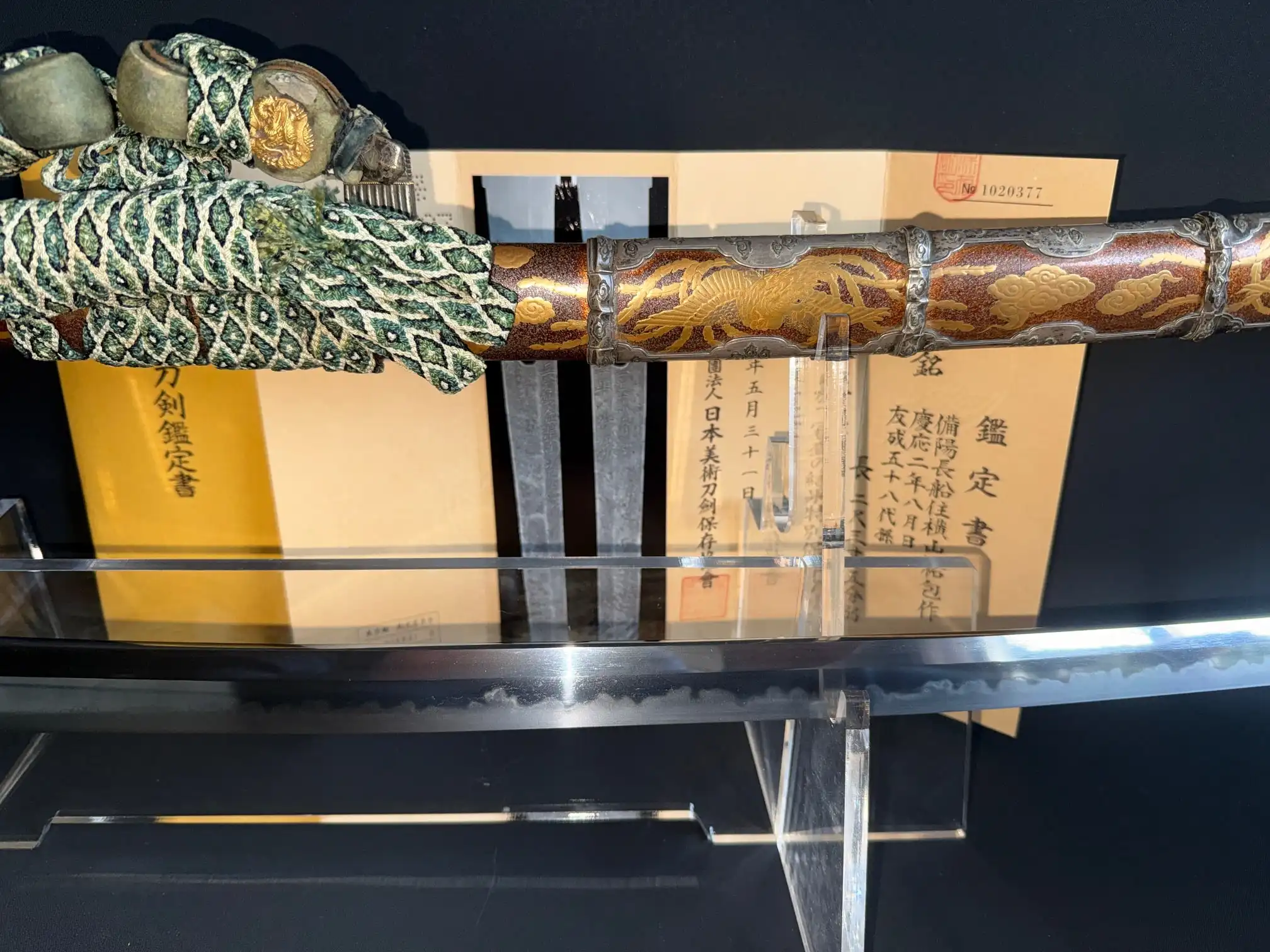 Close-up of Tachi Yokoyama Sukekane katana showing ornate tsuka and highly polished blade against certifications