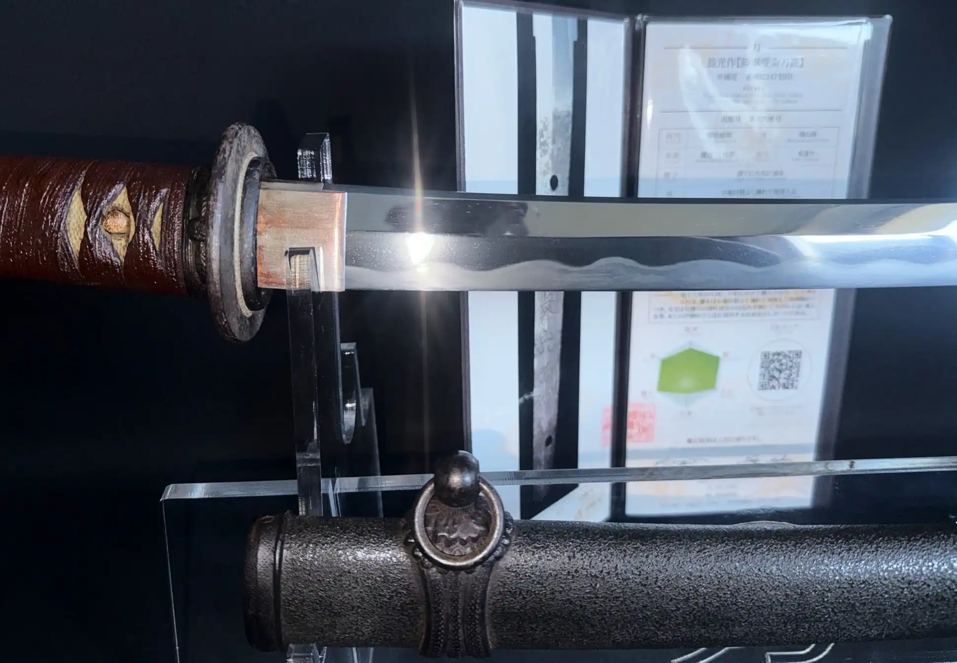 Close-up of a WWII Katana Ichihara Nagamitsu blade with a visible hamon and tsuka, alongside its saya.