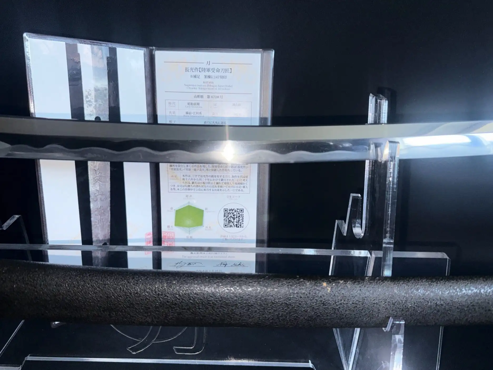 Close-up of a WWII Katana Ichihara Nagamitsu blade with an information card behind it.