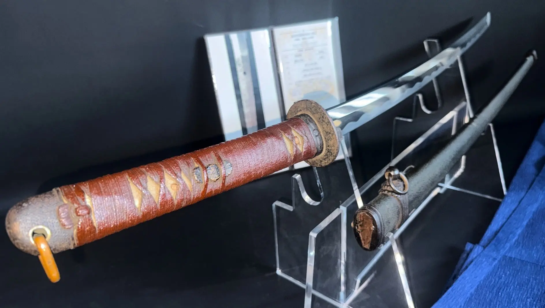 Red-wrapped handle of a WWII Katana Ichihara Nagamitsu with blade and scabbard on display