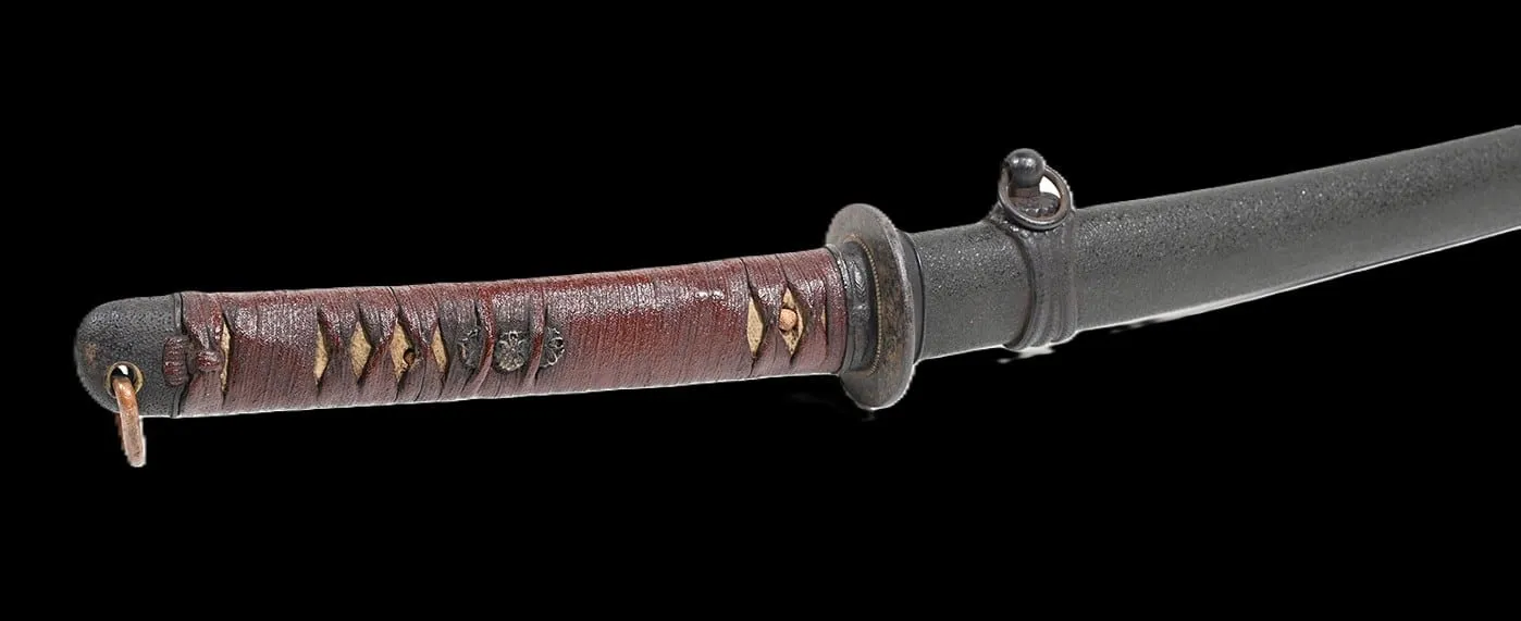 Close-up of a WWII Katana Ichihara Nagamitsu scabbard and brown tsuka wrap with traditional gilded menuki