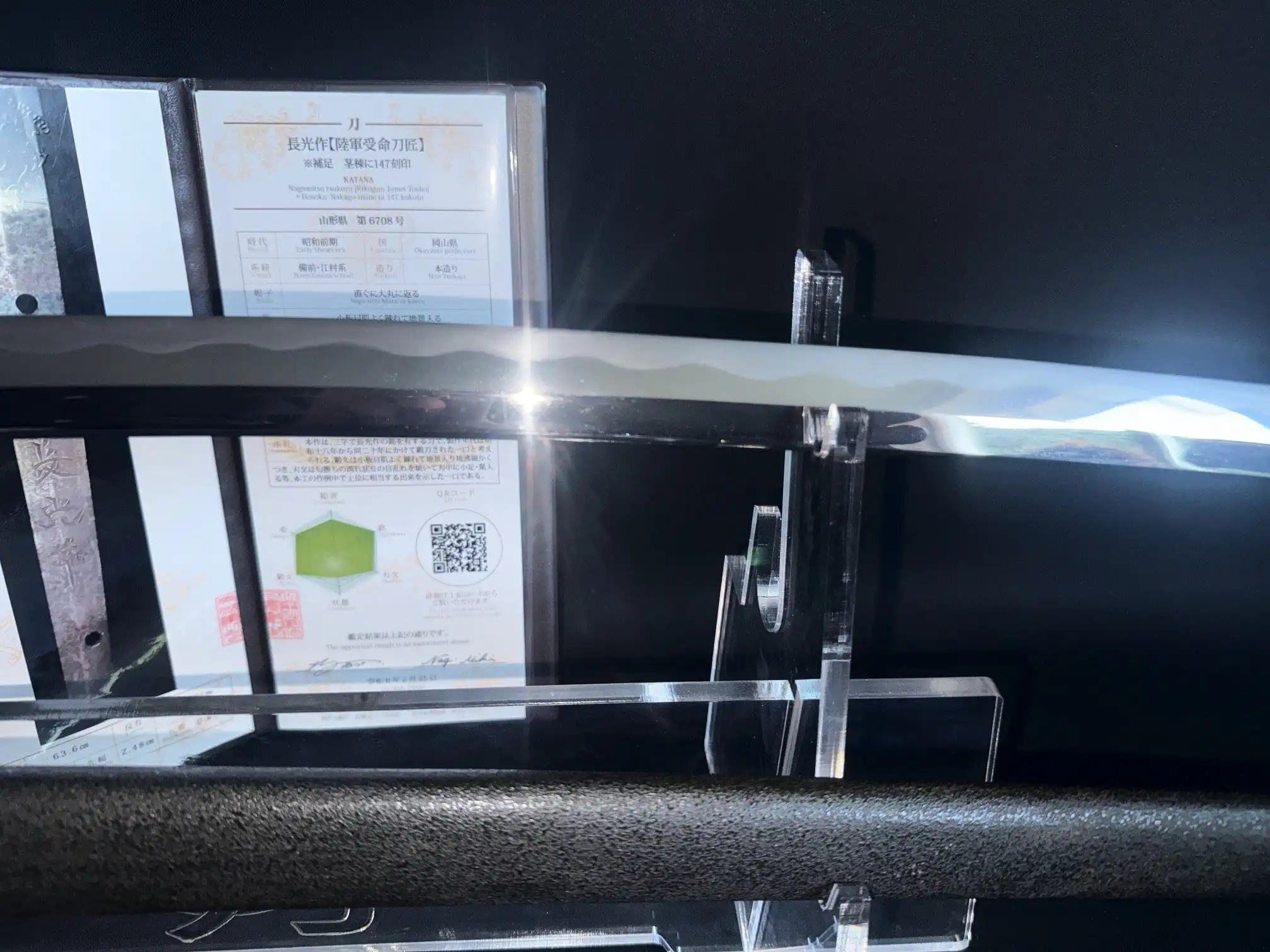 Shinogi-zukuri blade of WWII Katana Ichihara Nagamitsu displayed horizontally on a stand with paperwork