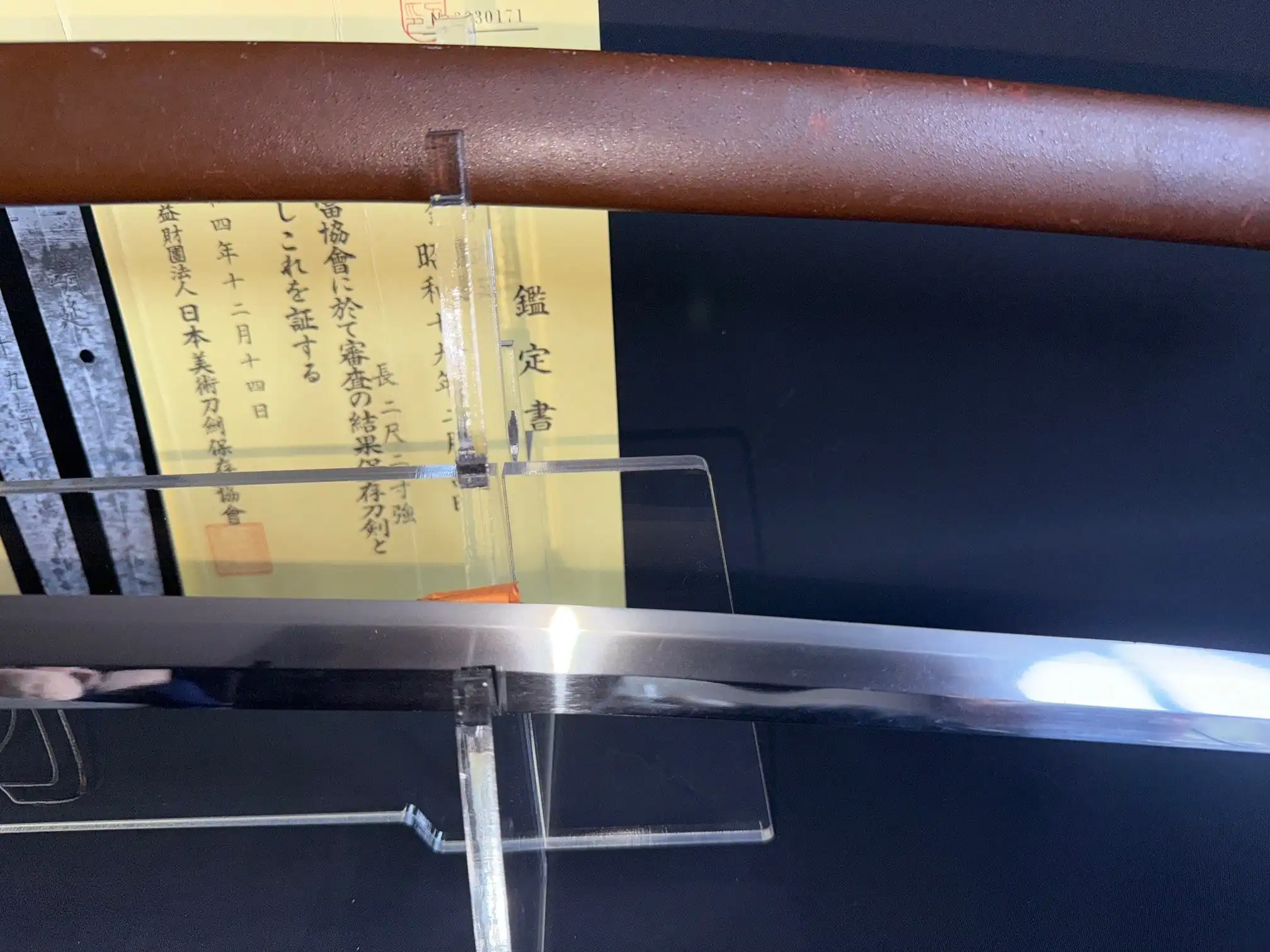 Reflective Yasukuni Gendaitō Yasunobu katana with scabbard & Japanese certificate visible from the side