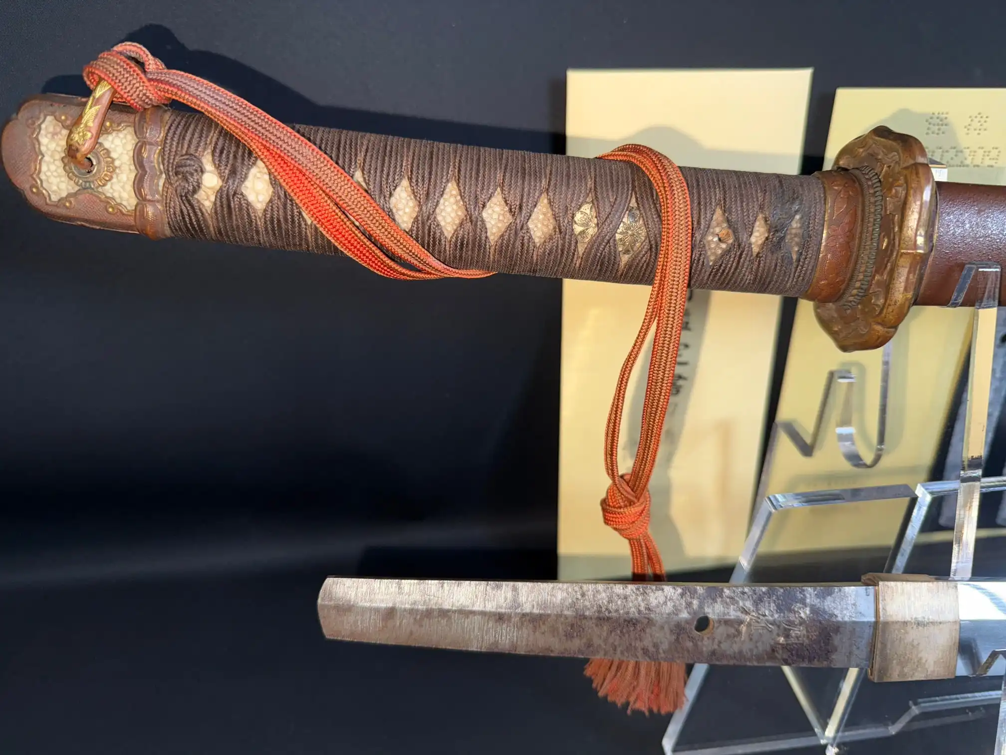 Close-up 1944 Yasukuni Gendaito Yasunobu Katana with braided brown tsuka and orange sageo.