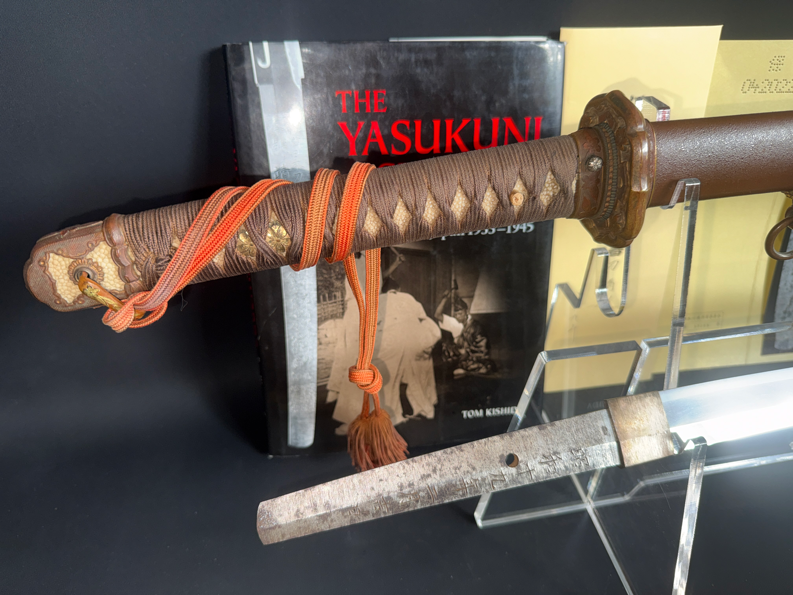 Close-up of a Yasukuni Gendaitō Yasunobu katana, showing its brown tsuka, orange ito, and visible tang.