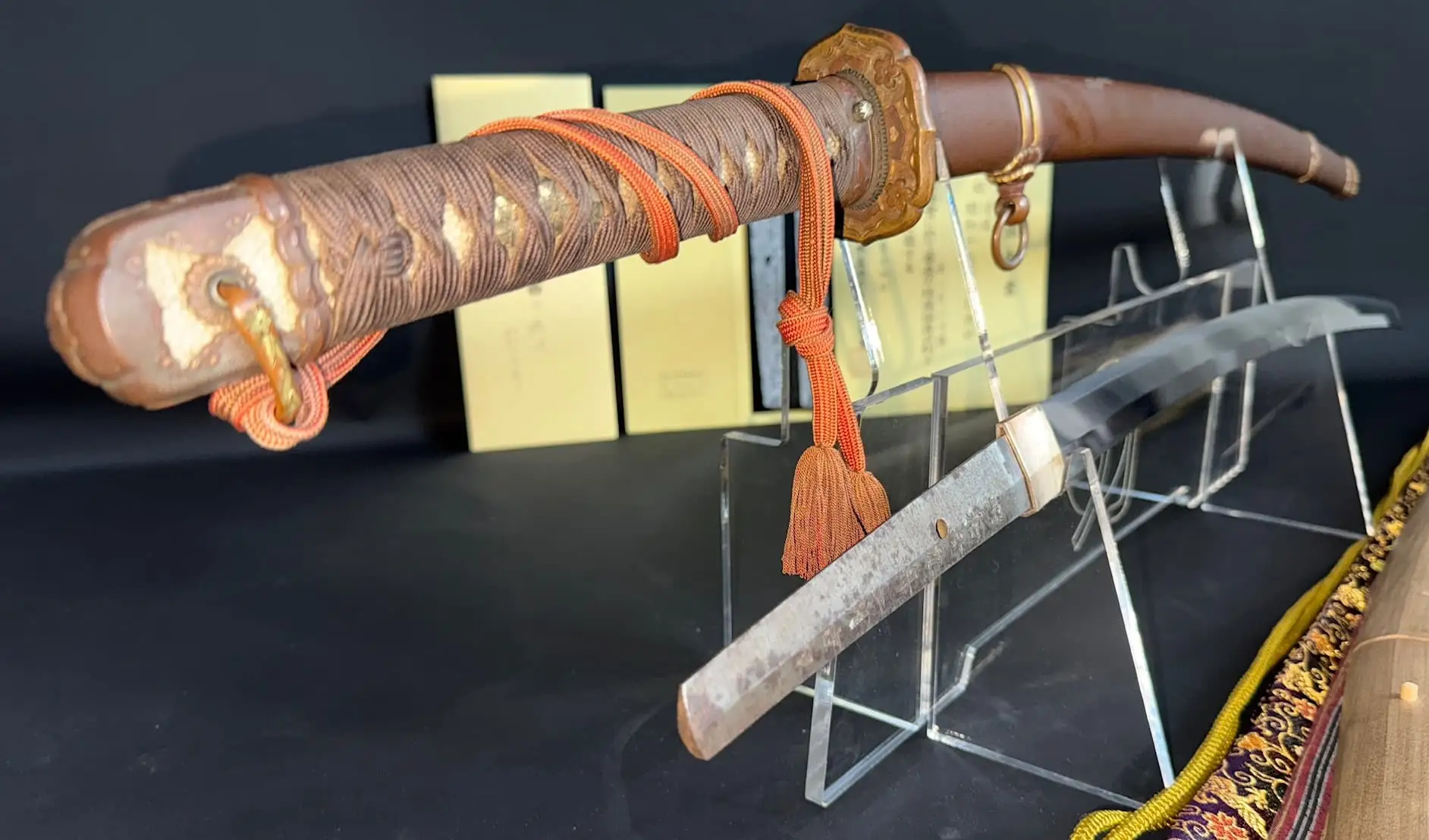 Yasukuni Gendaitō Yasunobu katana with visible tang on display, hilt wrapped with orange cord
