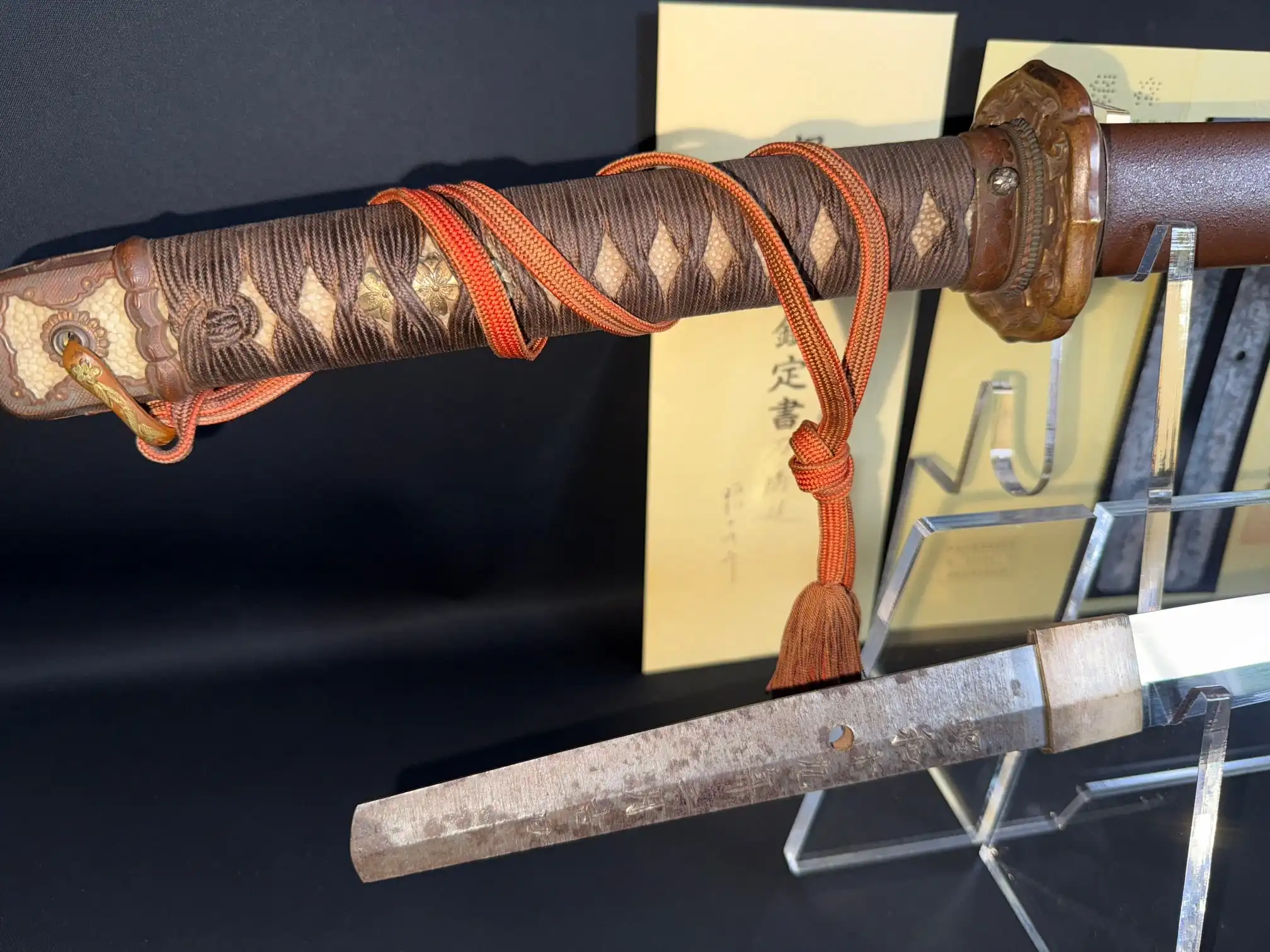 Partial view of a Yasukuni Gendaitō Yasunobu katana, showing the handle with orange cord and part of the blade
