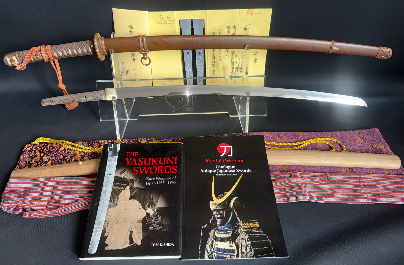 Yasukuni Gendaitō Yasunobu katana with scabbard, blade, and books on display