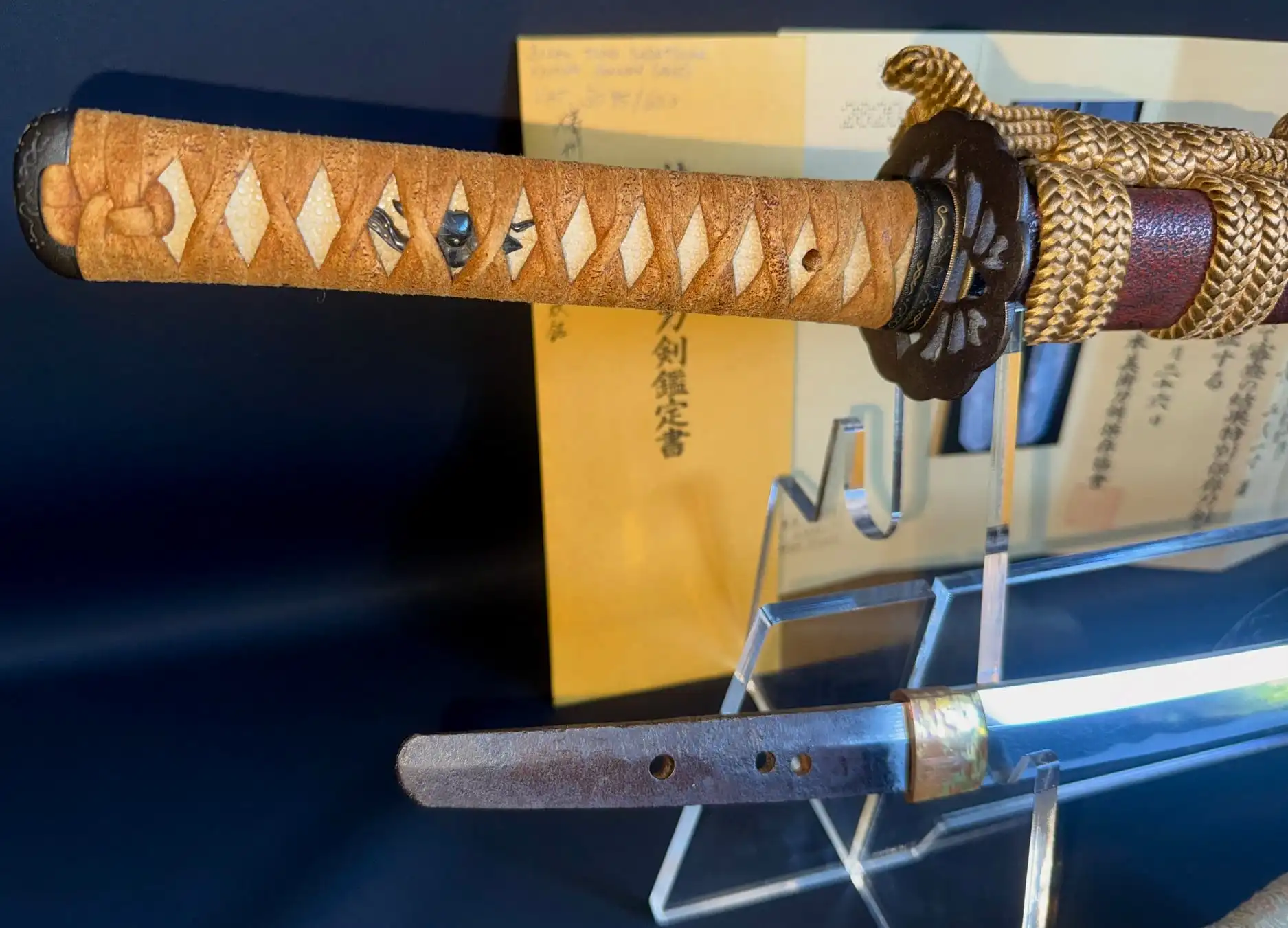 Close up of Katana Bishū Tomo-jū Sadatsugu handle with ray skin inlay and braided ito against the blade.