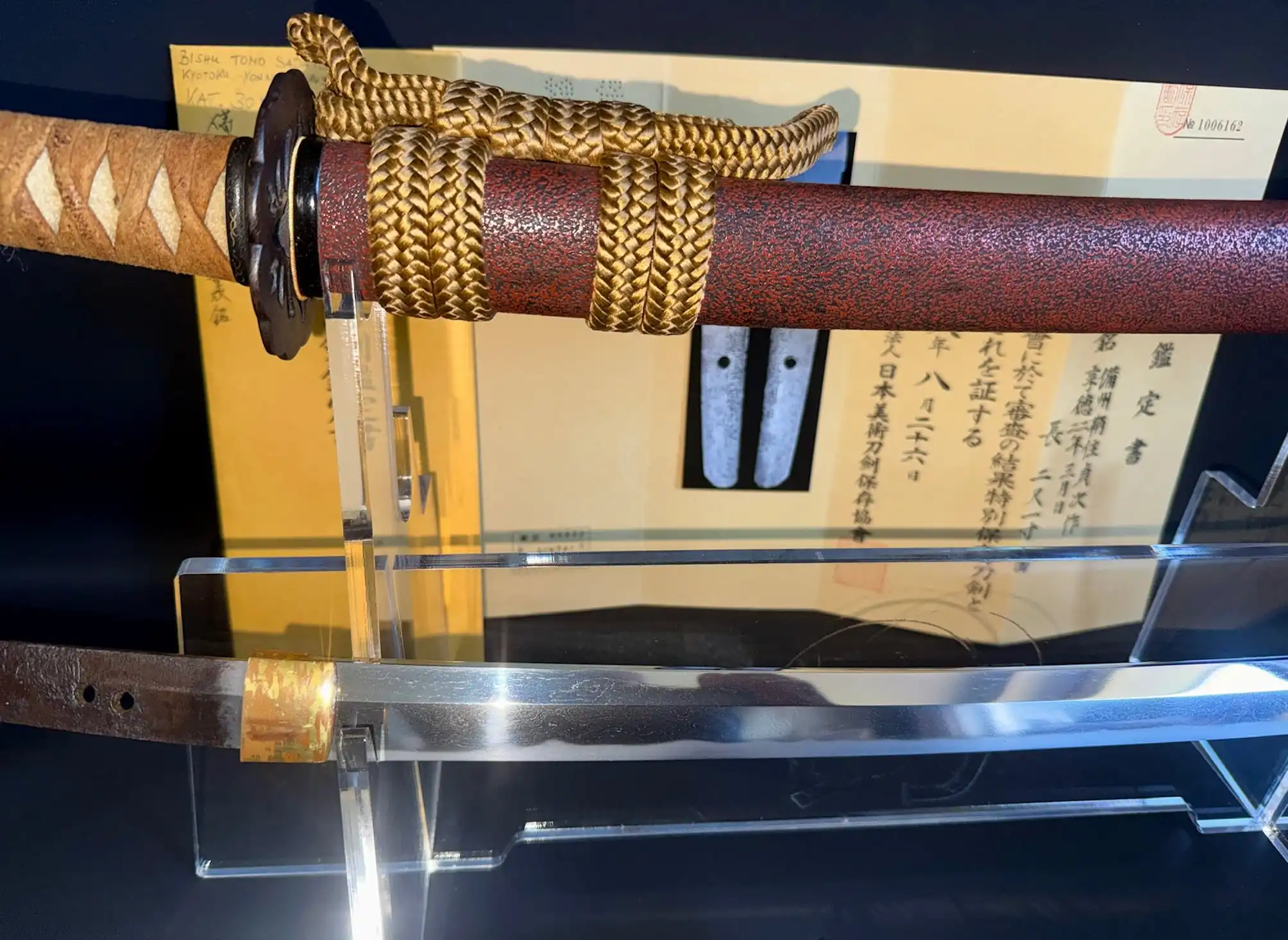 Katana Bishū Tomo-jū Sadatsugu, hilt, scabbard, and blade detail on display with documents