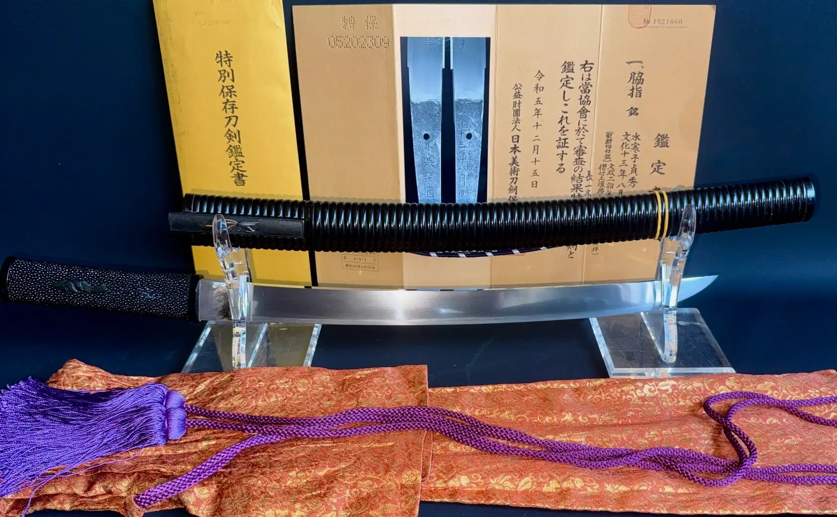 Suishinshi Masahide Wakizashi in black scabbard, displayed with certificate and purple cord from above.