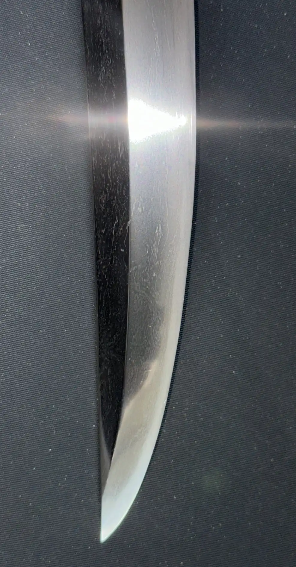 Close-up of the polished edge and tip of the Aoe Nagamaki-Naoshi Katana blade, showing reflections.