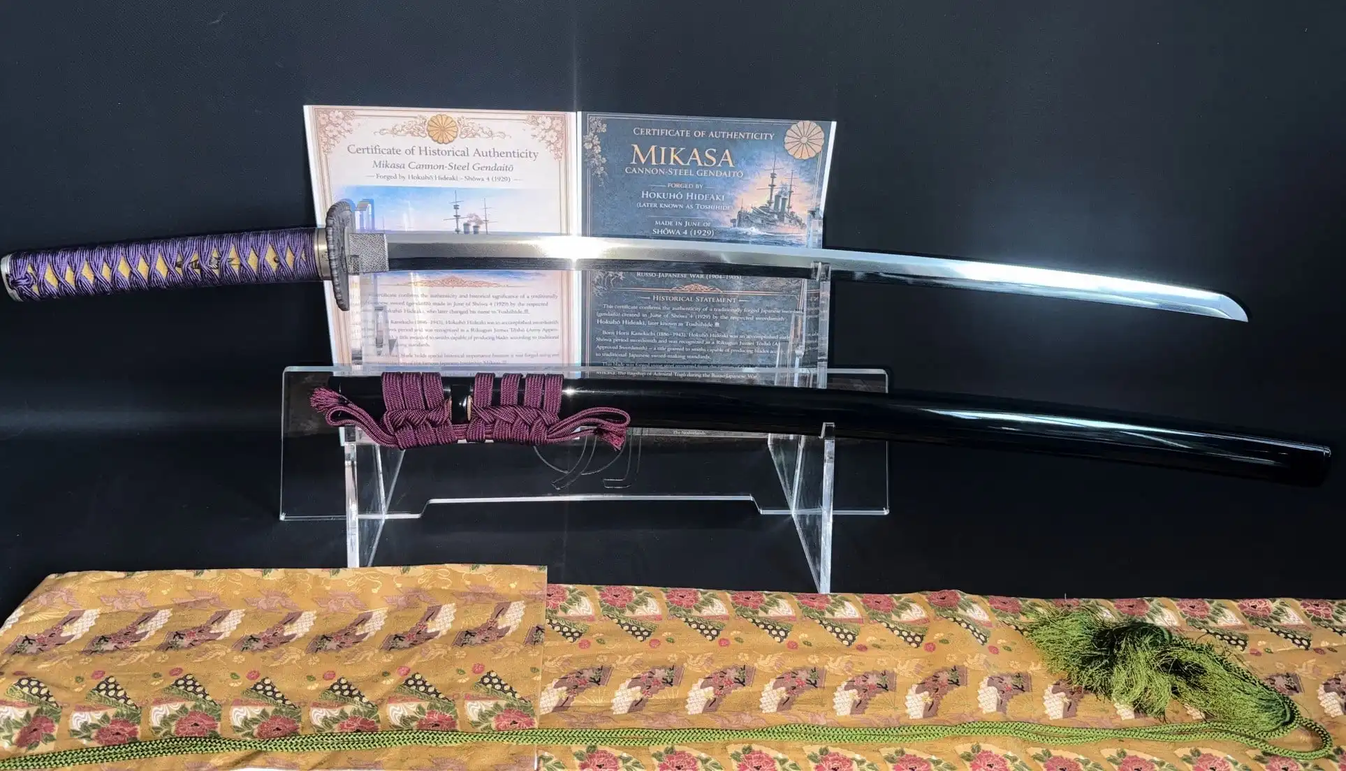 Gendaitō Battleship Mikasa katana on display with scabbard, certificates and fabric cloth, top-down view.