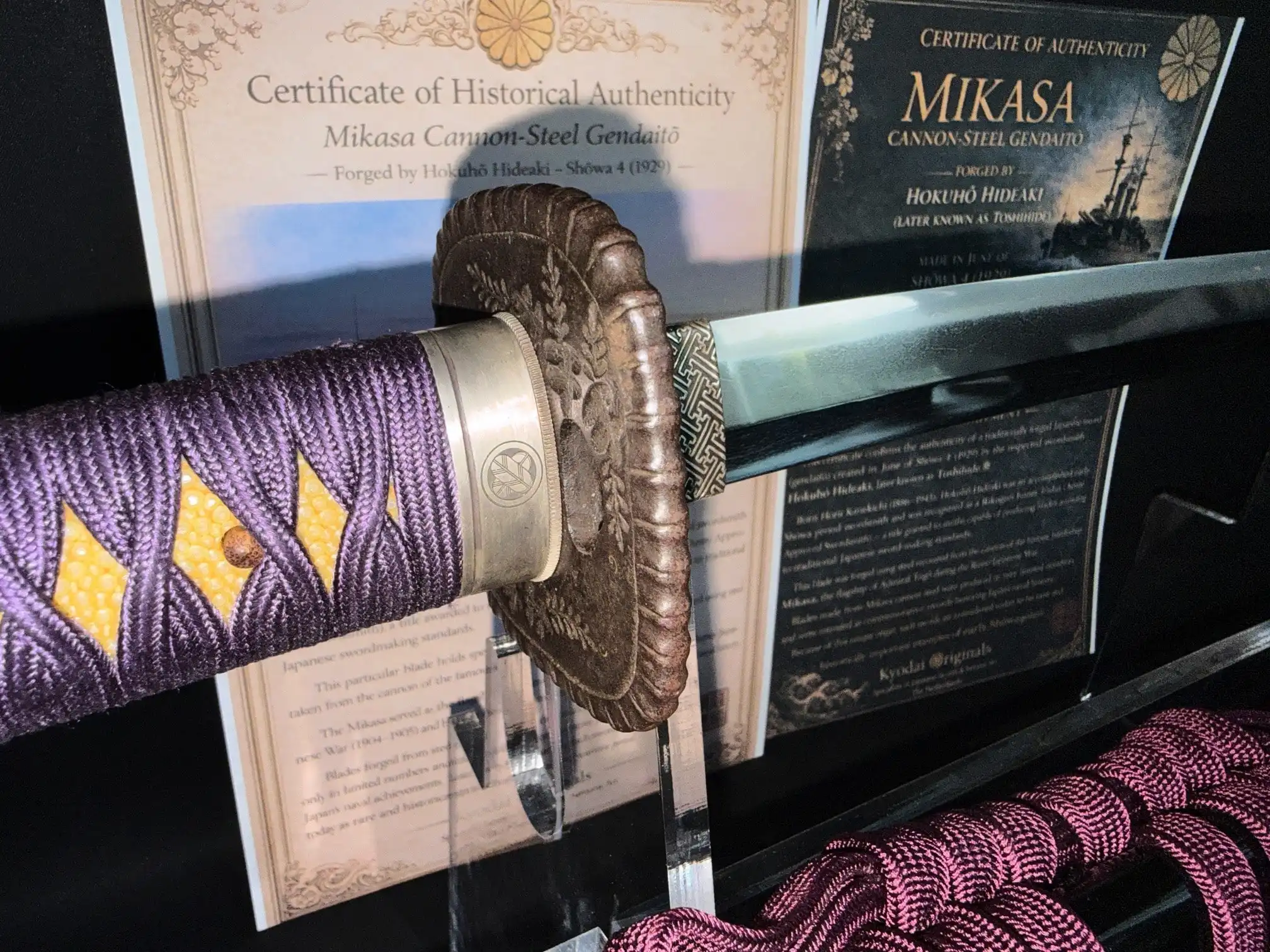 Close up of Gendaitō Battleship Mikasa katana showing purple tsuka-ito and bronze tsuba.