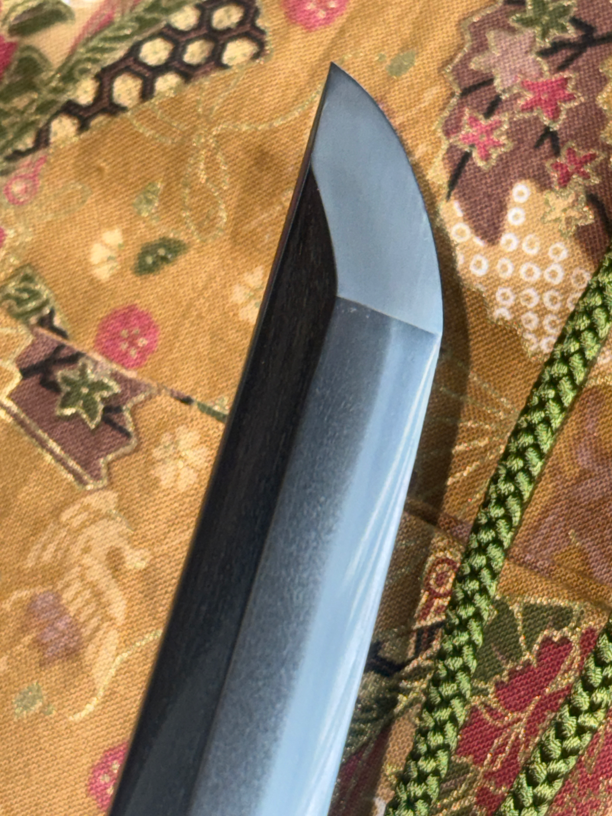 Close-up of a Gendaitō Battleship Mikasa katana blade tip, showing its fine polish over Japanese fabric