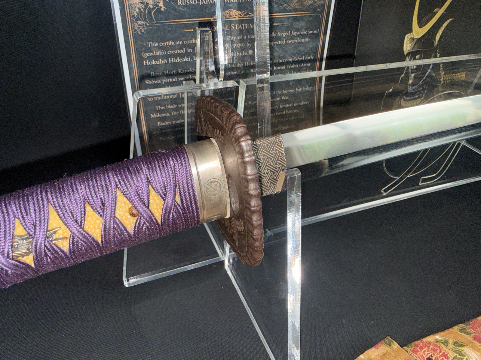 Close-up of a Gendaitō Battleship Mikasa katana showing purple tsuka-ito and detailed tsuba.