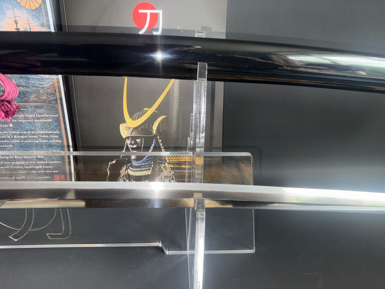 Close-up of a Gendaito Battleship Mikasa katana blade and scabbard on display, with historical text.