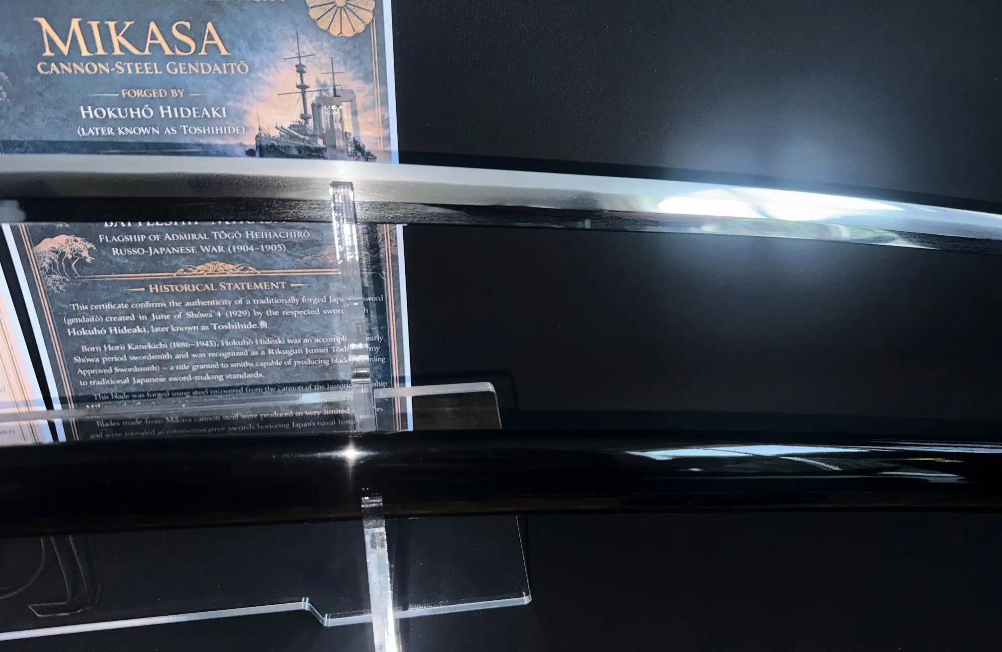 Close-up of a gleaming Gendaito Battleship Mikasa katana blade next to its historical statement