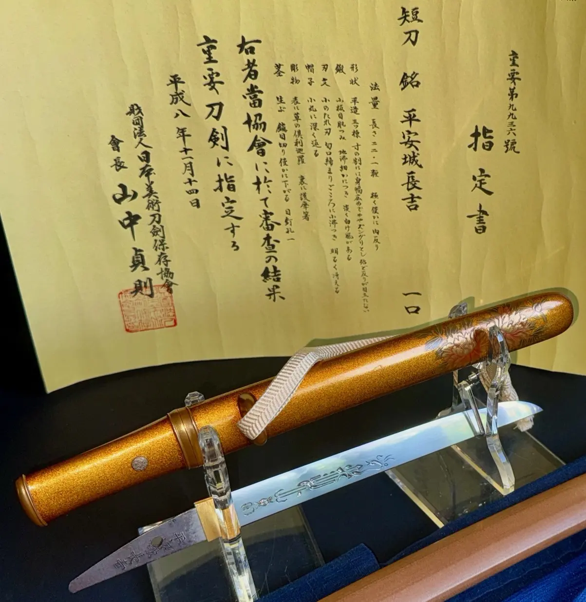NBTHK Jūyō Tōken Tantō by Heianjō Nagayoshi with a golden scabbard and detailed blade, displayed on a stand.