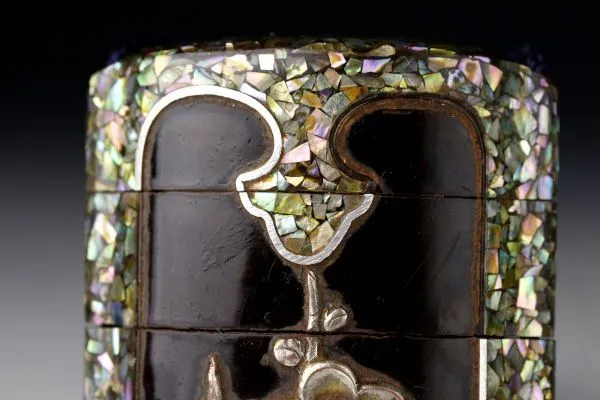 Detail of an Edo Japanese Inro accessory with iridescent mother-of-pearl inlay against dark lacquer