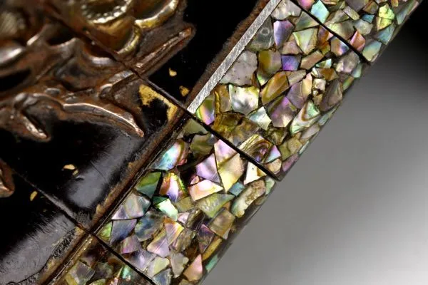 Close-up of an Edo Japanese Inro accessory with intricate mother-of-pearl inlay and textured gold elements.