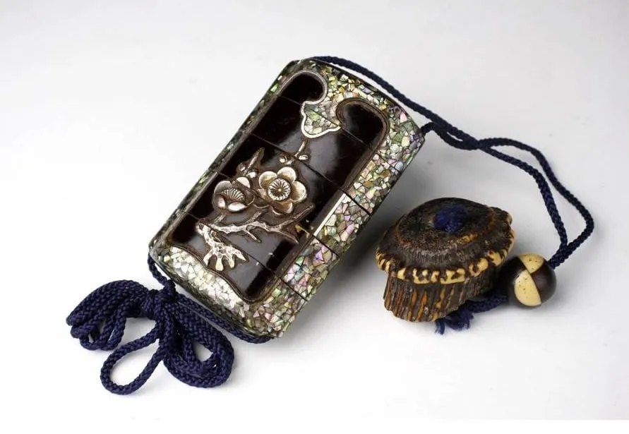 Ornate Edo Japanese Inro accessory with mother-of-pearl inlay and floral design, alongside a netsuke.