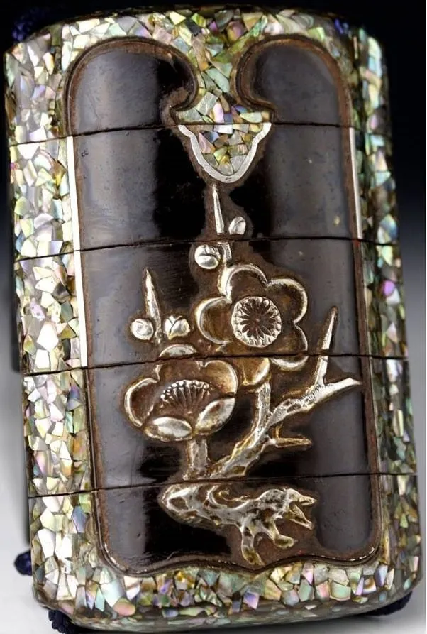 Close-up of an Edo Japanese Inro accessory, dark wood with mother-of-pearl inlay and silver botanical motif.