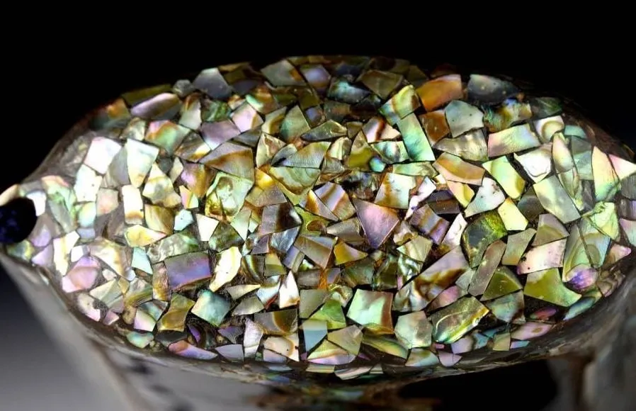Close-up of an Edo Japanese Inro accessory top, adorned with intricate, iridescent mother-of-pearl inlay.