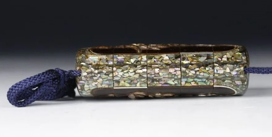 Side view of a segmented Edo Japanese Inro accessory with mother-of-pearl inlay and blue cord.